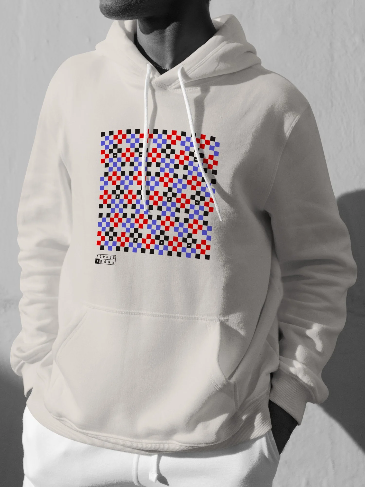 A person wearing a white hoodie with a pixelated abstract graphic design in black, red, and blue on the front.