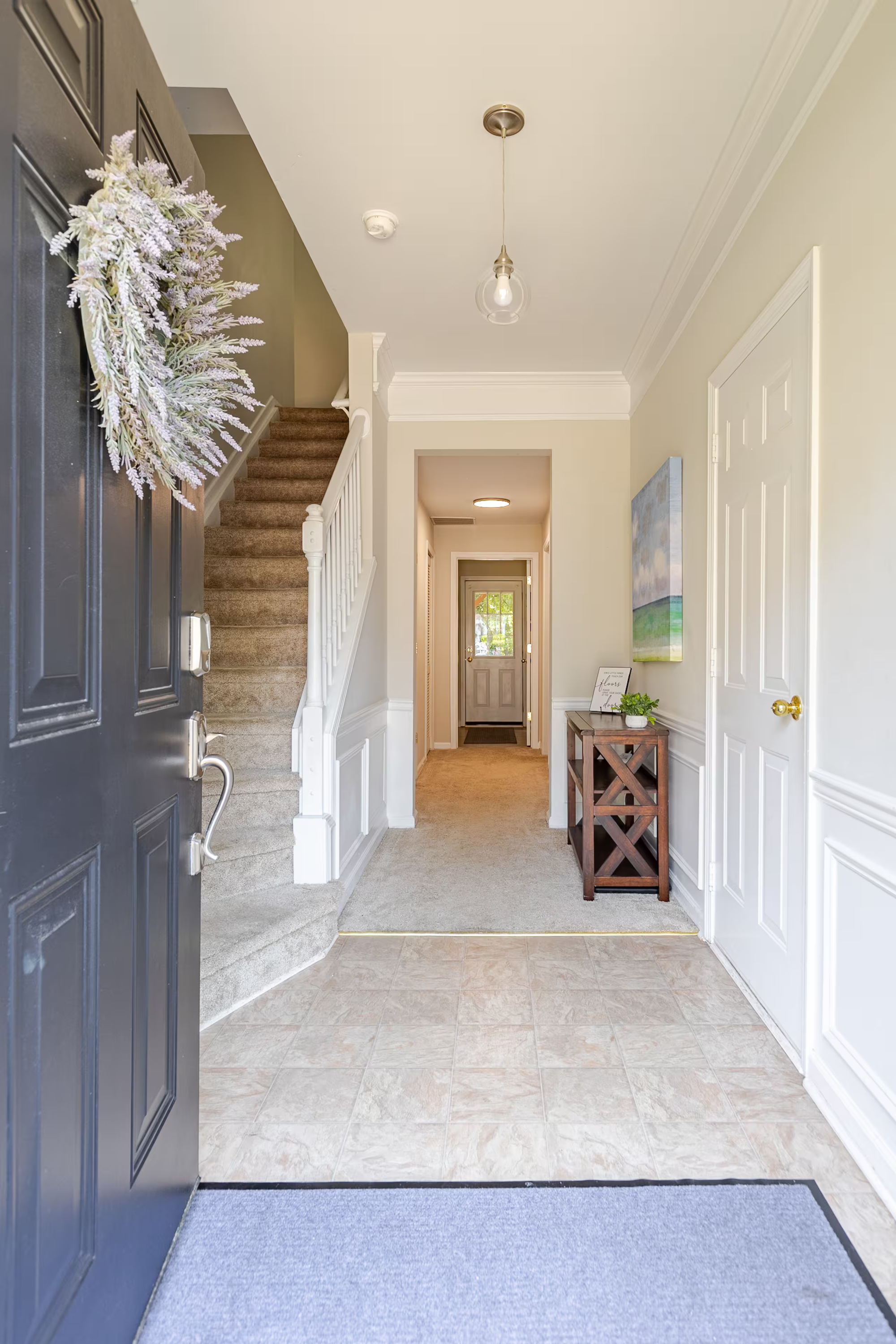 View of a home's front entrance with an open door, foyer, staircase, hallway, and a piece of wall art, inviting people into the Loveland Airbnb.