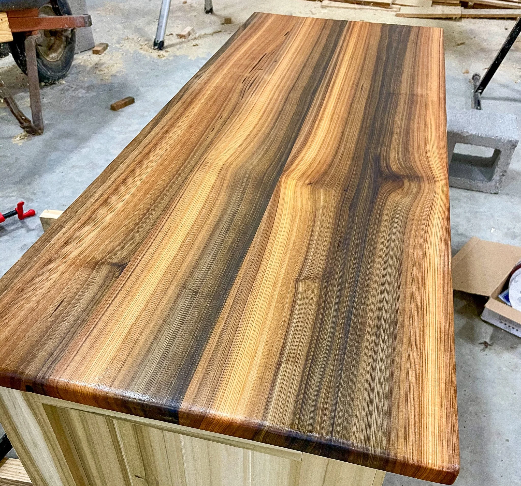 A recently finished wooden tabletop with a smooth, polished finish showcasing natural wood grain patterns and various shades of brown.