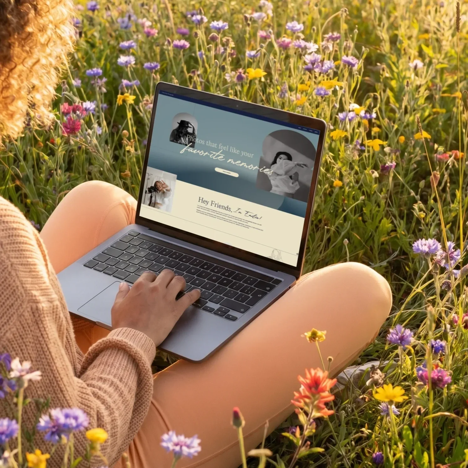 A person sitting in a field of colorful wildflowers using a laptop.
