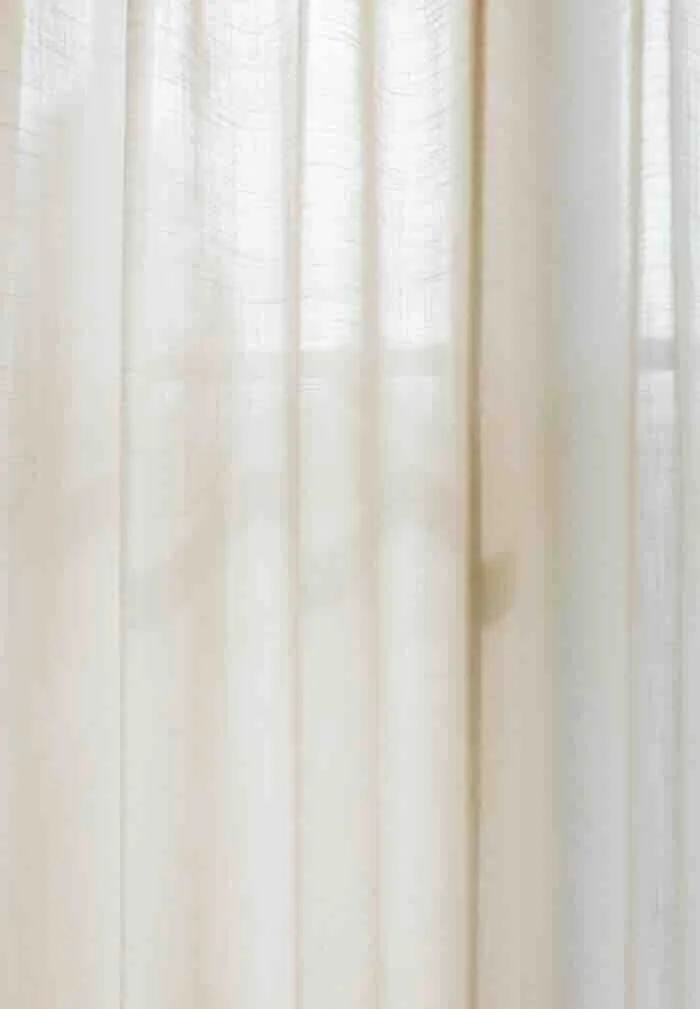 A gentle close-up of cream-colored linen curtains filtering soft daylight, symbolizing the calm and grounded space needed to begin therapy.