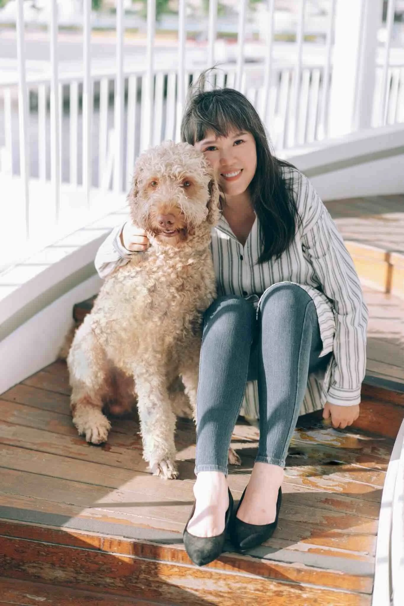 FuFan Chiang, a licensed therapist, sitting warmly on a sunny wooden deck with her dog, offering a welcoming smile for clients seeking online therapy in New York City and Utah.