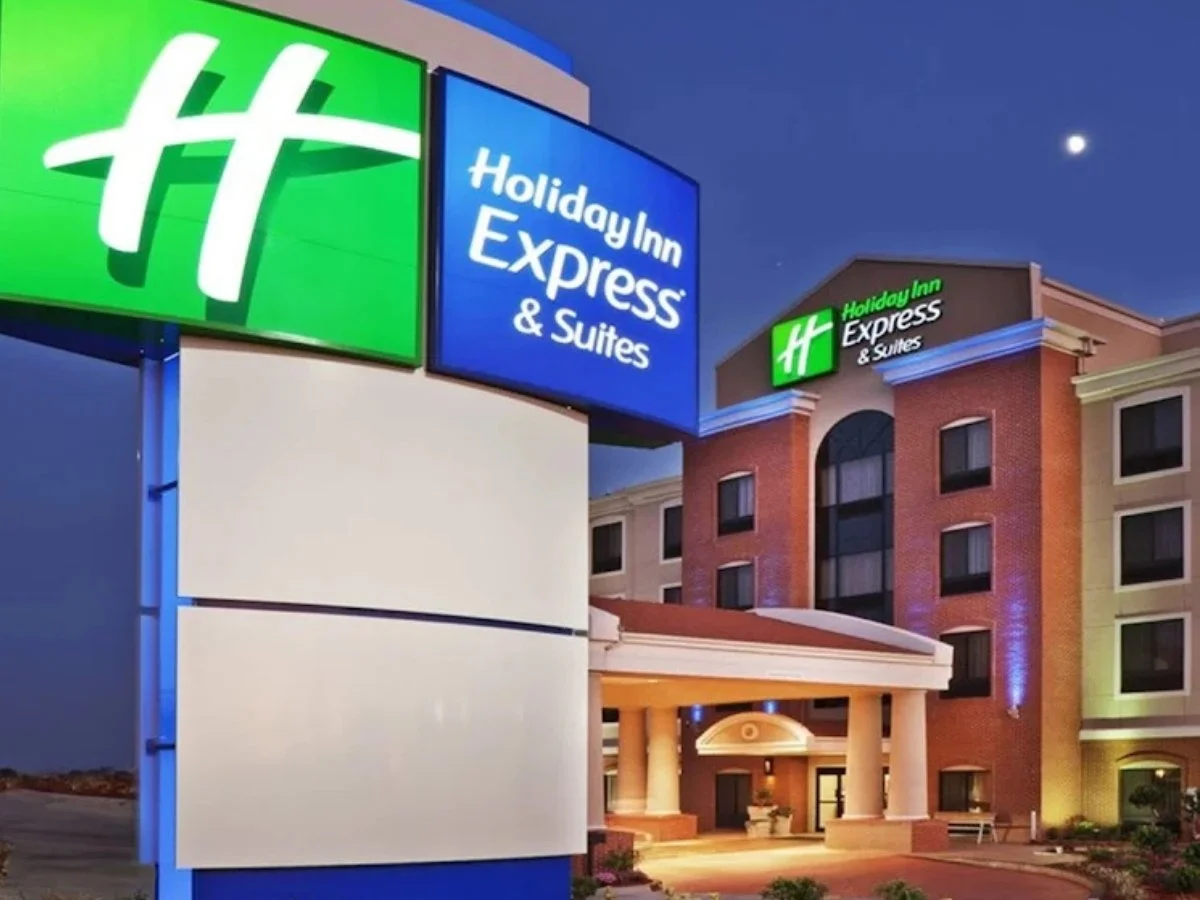 Exterior of a Holiday Inn Express & Suites hotel at night with illuminated signs.
