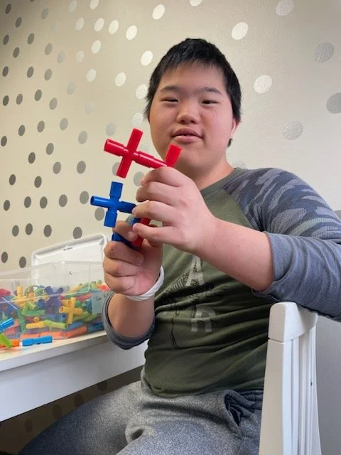 A high school boy is holding up a structure he designed
