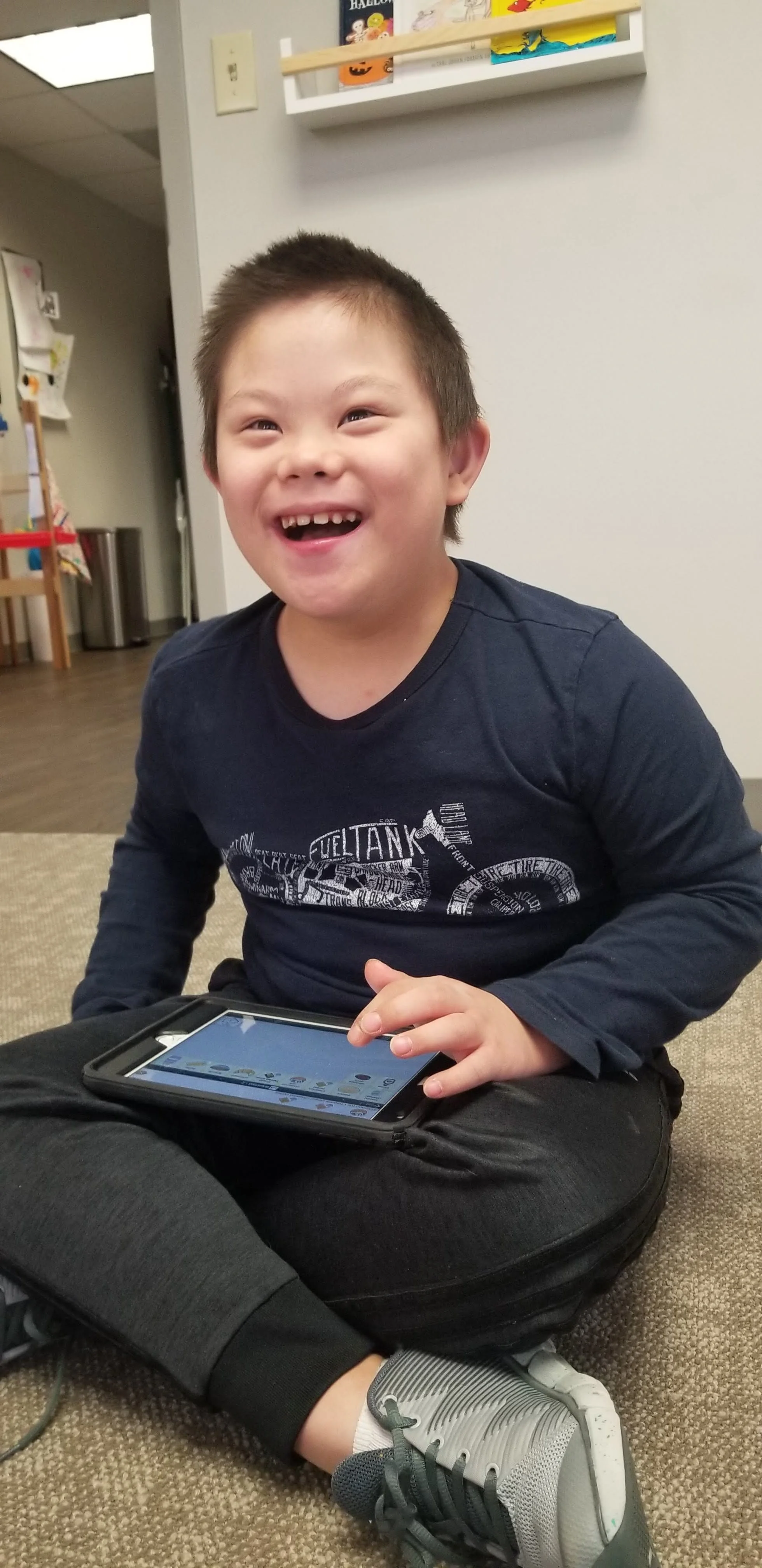 A boy smiling using a communication device