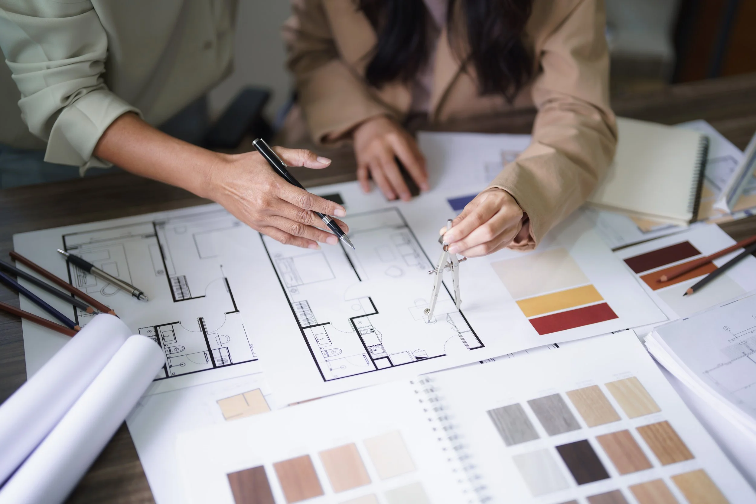 Design plans for a building or house on a table with color samples and architectural tools.