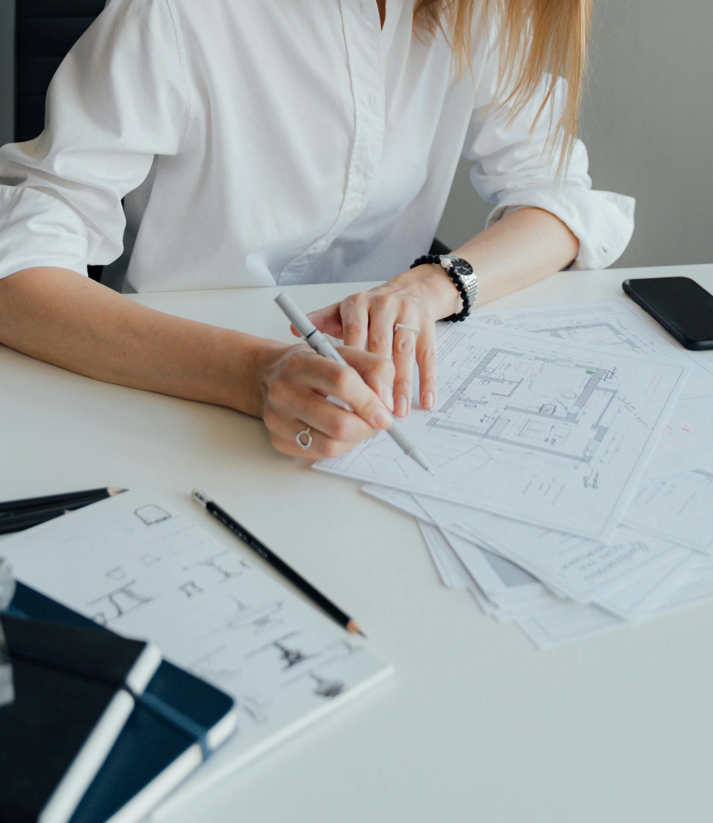 Female architect in white shirt writing on architectural blueprints in an office setting in Rochester New York