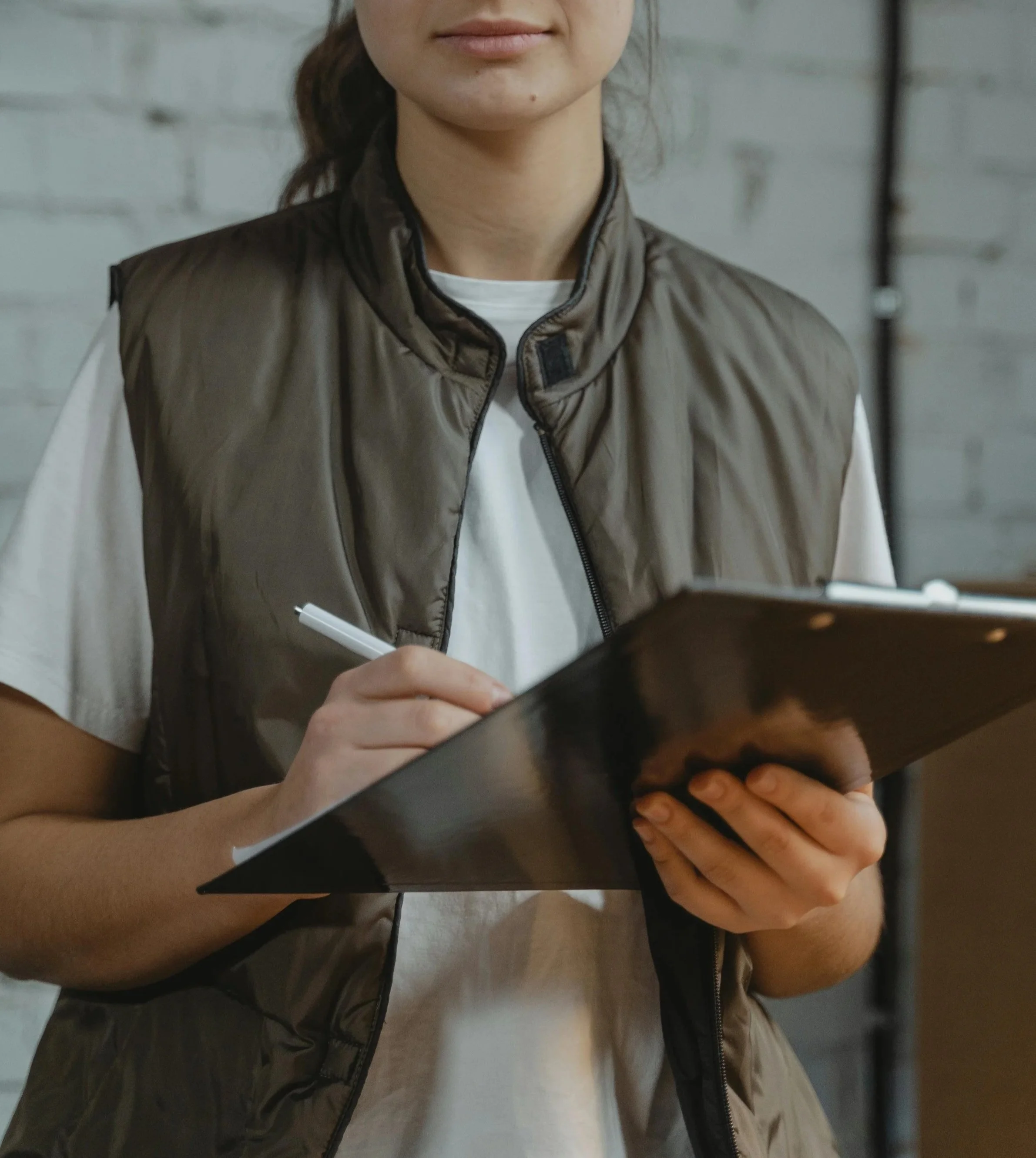 A woman on a construction site holding a pen and a tablet to take architectural planning notes