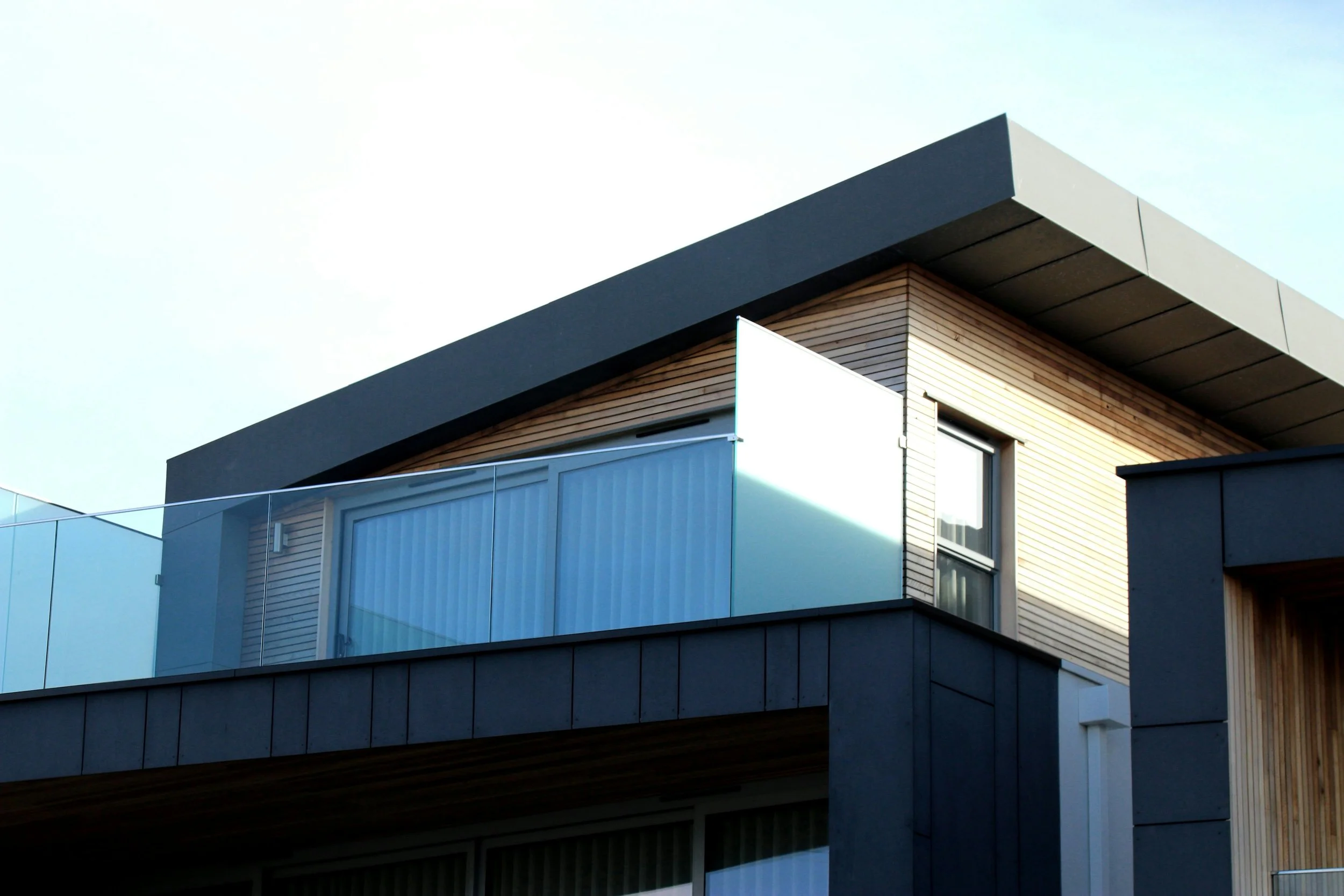 Close-up view of a modern architectural building with wooden paneling, glass balconies, and large windows to represent architecture services