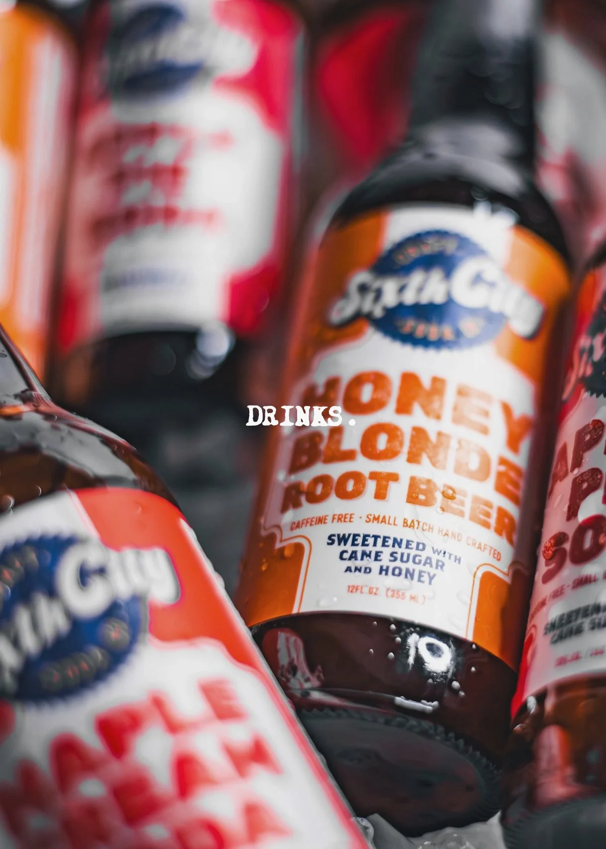 Close-up of a bottle of honey blond root beer with a label indicating it is caffeine-free, small batch crafted, sweetened with cane sugar and honey, and 12 fl oz (355 ml). Other similar bottles are partially visible around it.