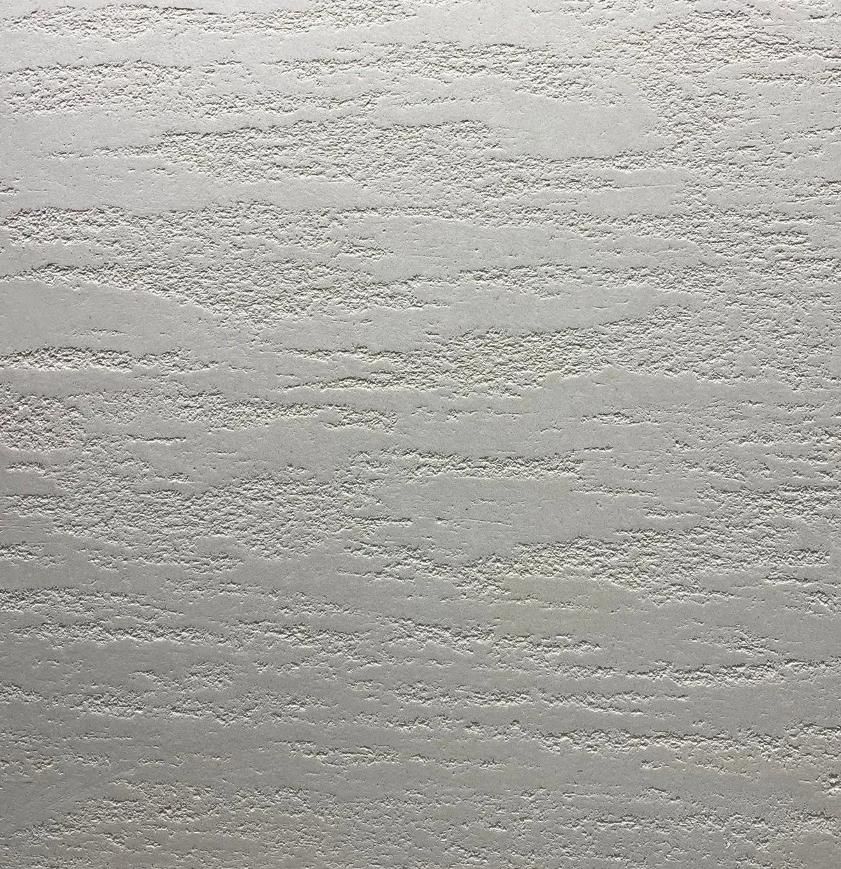 Close-up view of a textured white wall with a rough, uneven surface.