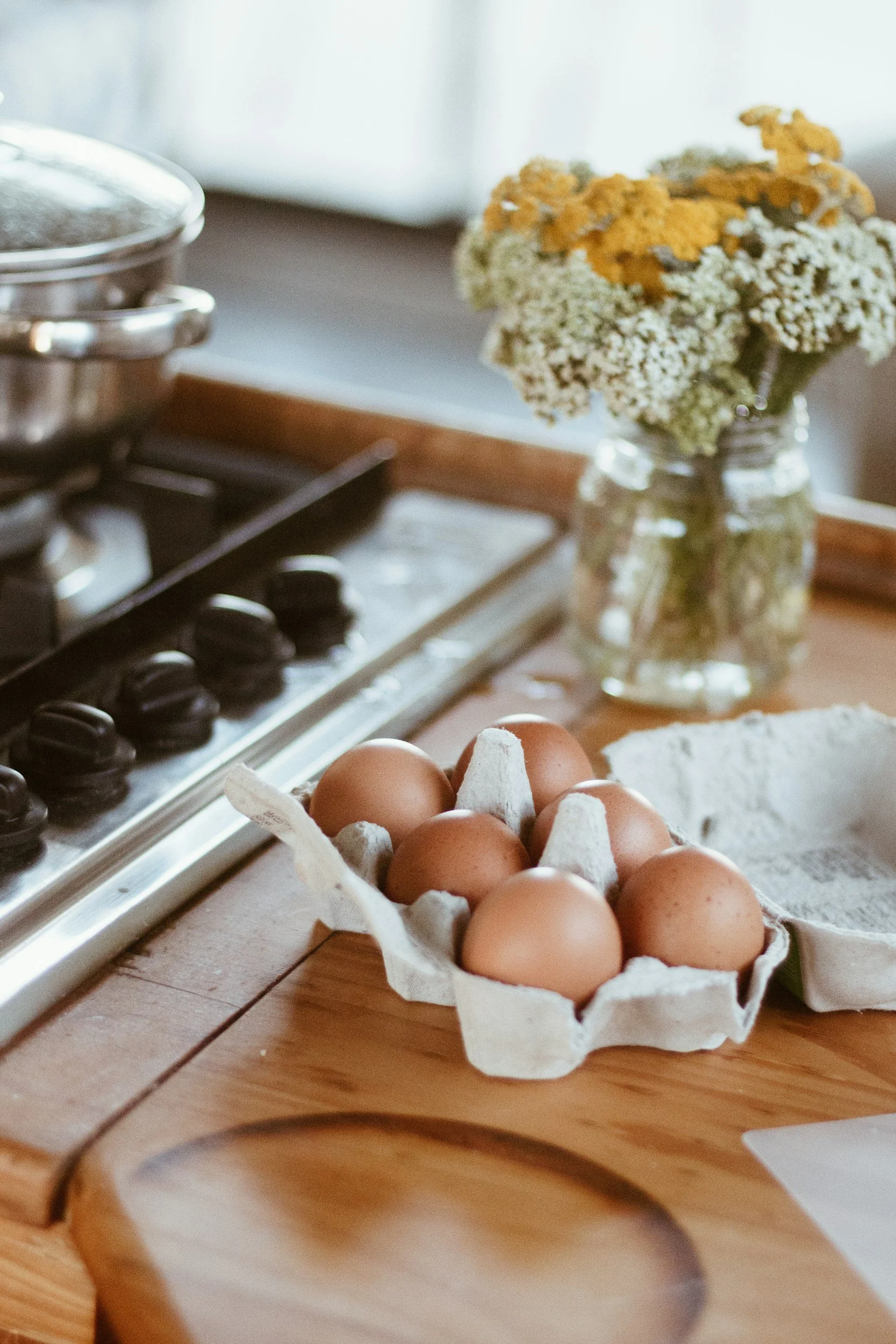A carton of brown eggs on a wooden countertop.