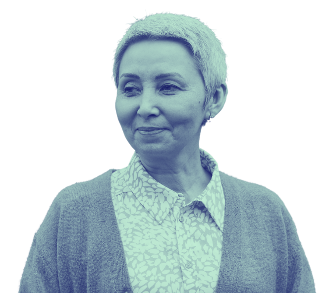 A woman with short gray hair wearing a patterned button-up shirt and a cardigan, smiling and looking to her left.