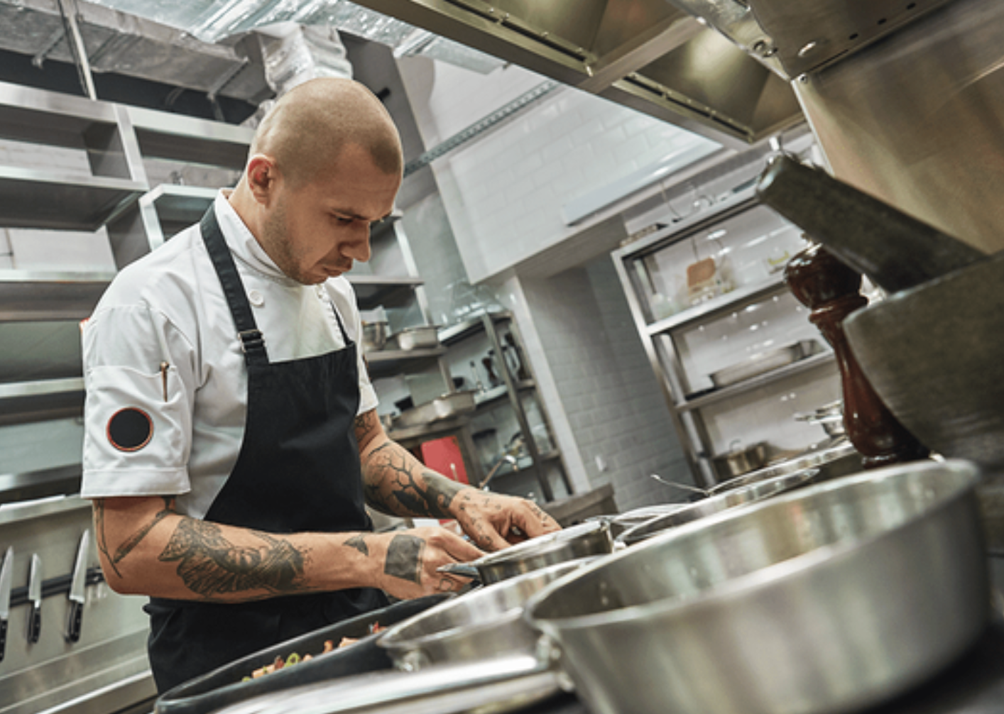 Chef in a kitchen with tattoos on his arms