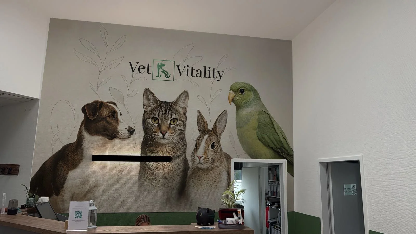 Wanddekoration im Tierarztpraxis Vet Vitality mit Bildern eines Hundes, einer Katze, eines Hasen und eines Papageis, mit den Worten Vet und Vitality.