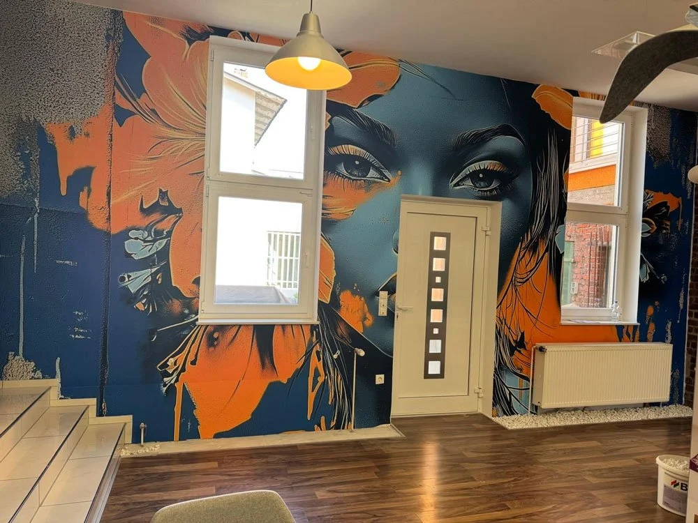 Wände mit einer Wandmalerei eines Frauenporträts in einer modernen Wohnung, mit zwei Fenstern, einer Tür mit quadratischen Glasfenstern, einem Heizkörper und Holzboden.