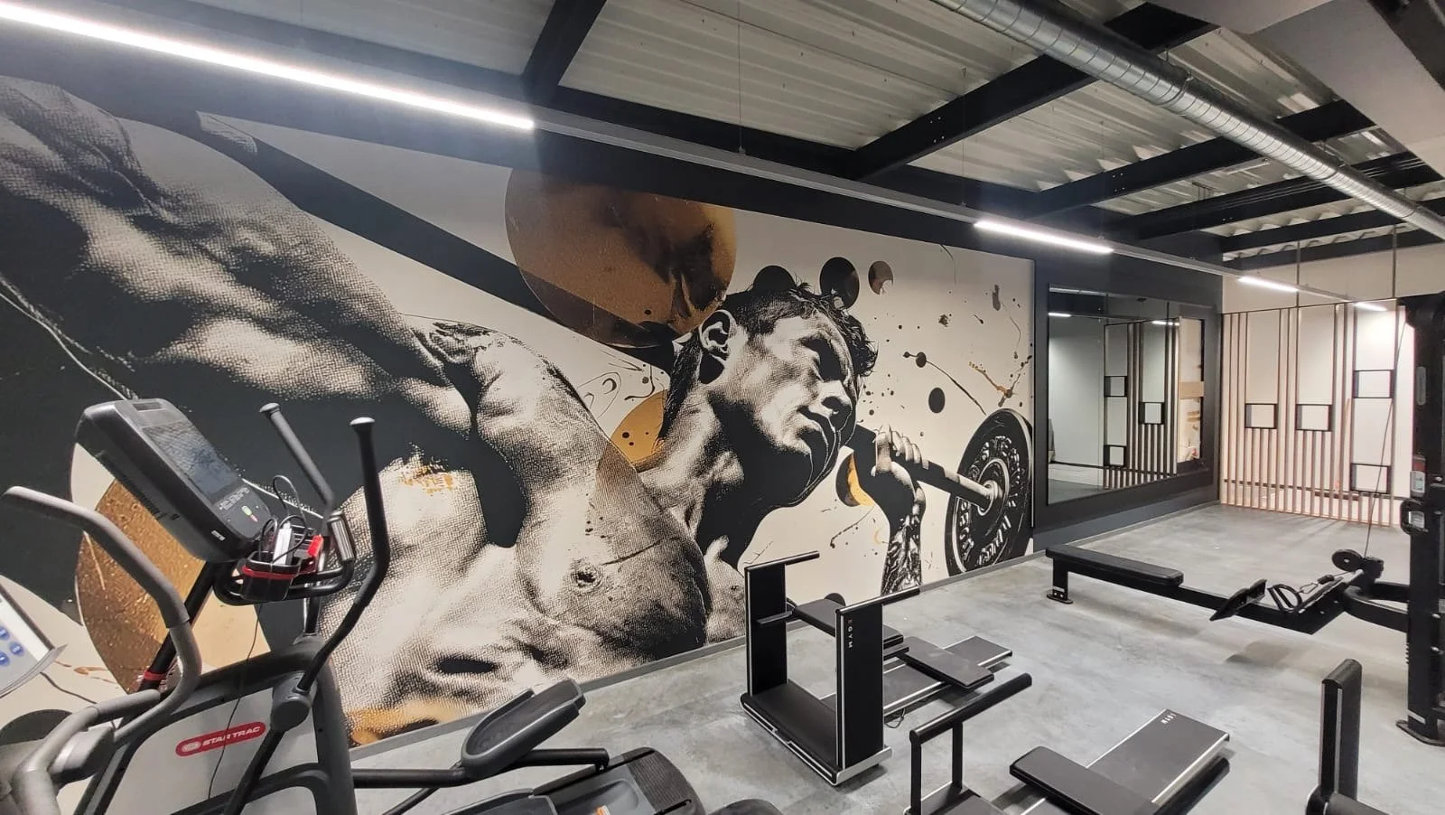 Fitnessraum mit Wandkunst, die einen männlichen Wrestler oder Boxer zeigt, der ein Gewicht hebt und in einem kraftvollen Moment ist.