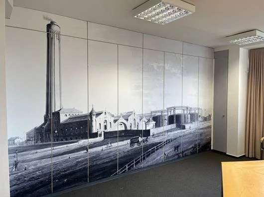 Wand mit großem Schwarz-Weiß-Fotodruck eines alten Bahnhofs oder Werkshalle in industriellem Stil.