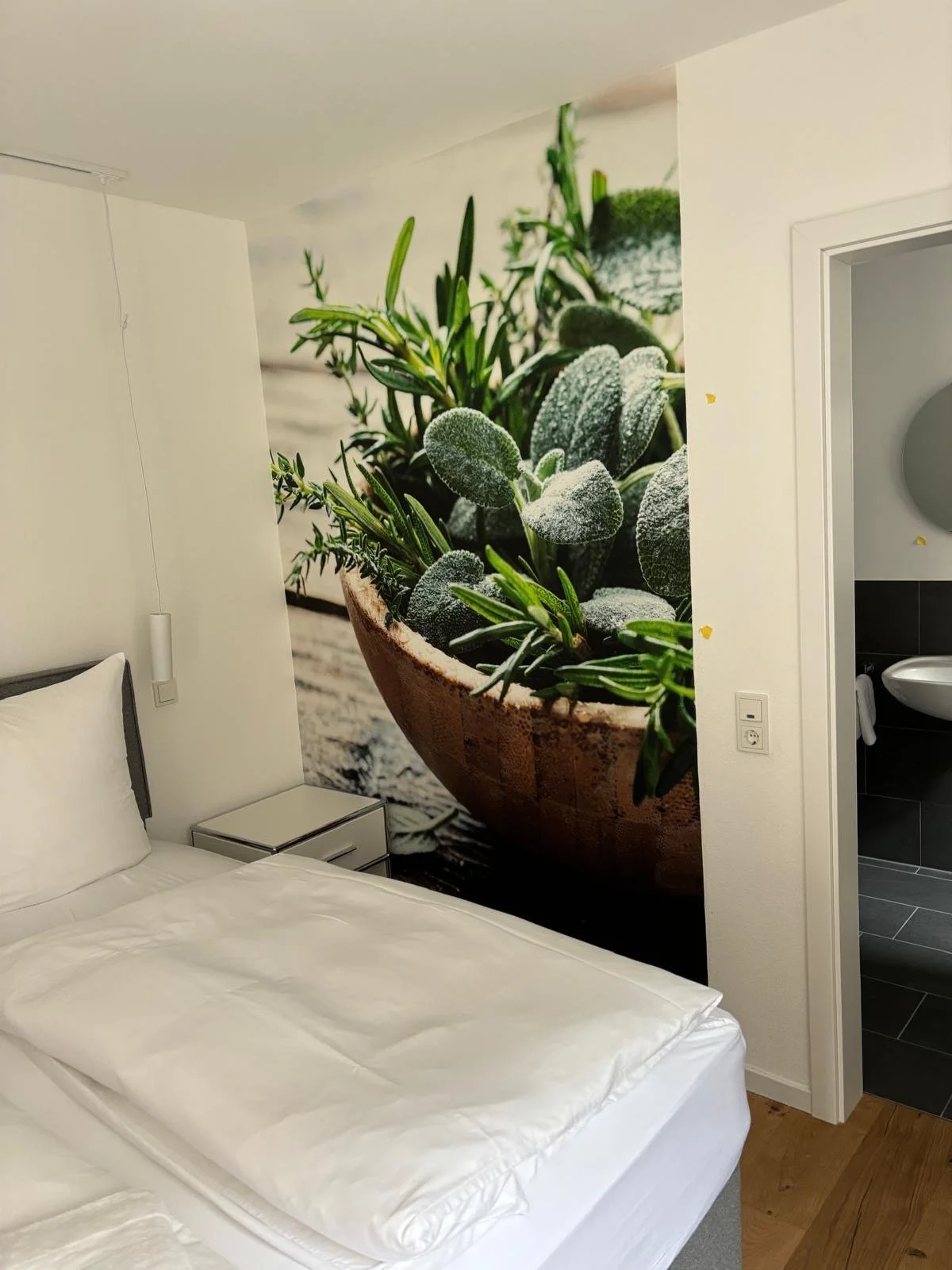 Bett in einem Zimmer mit einem Wandbild einer großen Topfpflanze