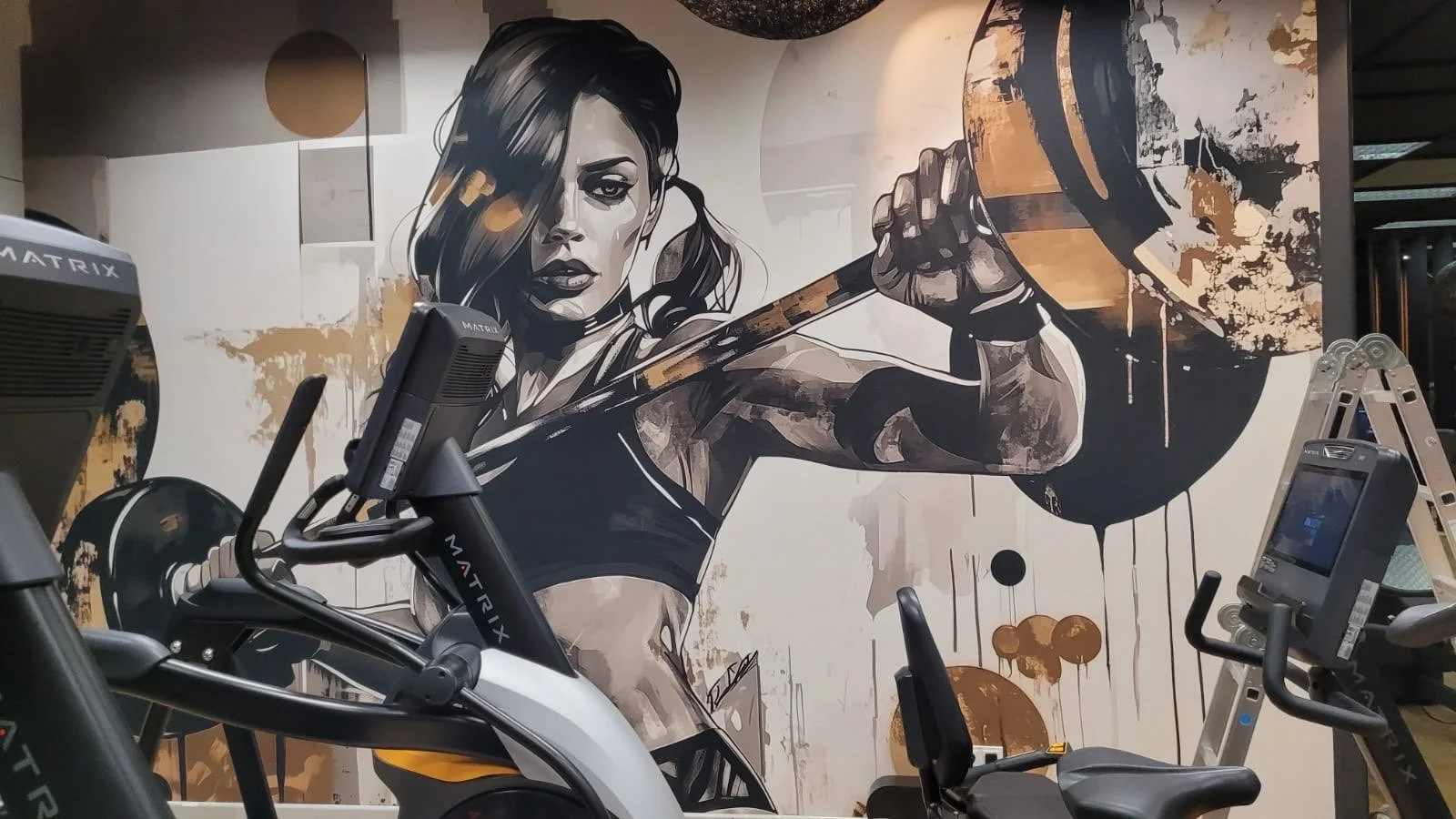 Muralszene einer athletischen Frau beim Boxen, mit einem Boxsack, in einer modernen Fitnessstudio. Die Wand im Hintergrund zeigt eine stilisierte Schwarz-Weiß-Graffiti-Illustration.