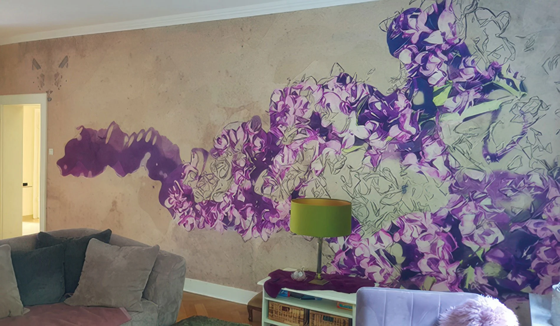Wohnzimmer mit Wandmalerei eines violetten Blumenstraußes, graues Sofa, Beistelltisch mit grüner Lampe.