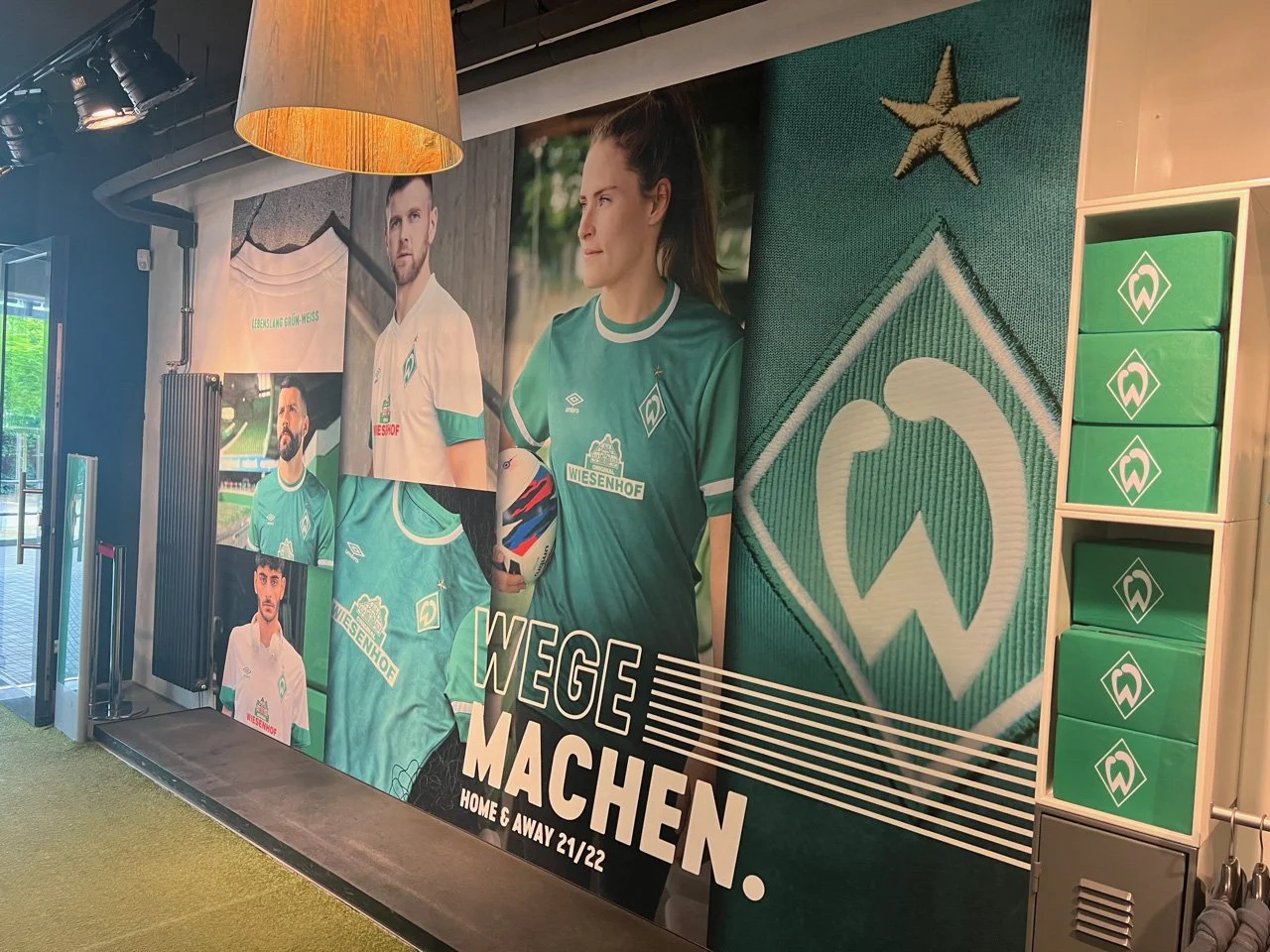 Verschiedene Fotos von Spielern des Fußballvereins Werder Bremen, mit dem Vereinslogo und Text "Weg machen. Home & Away 21/22" im Hintergrund.