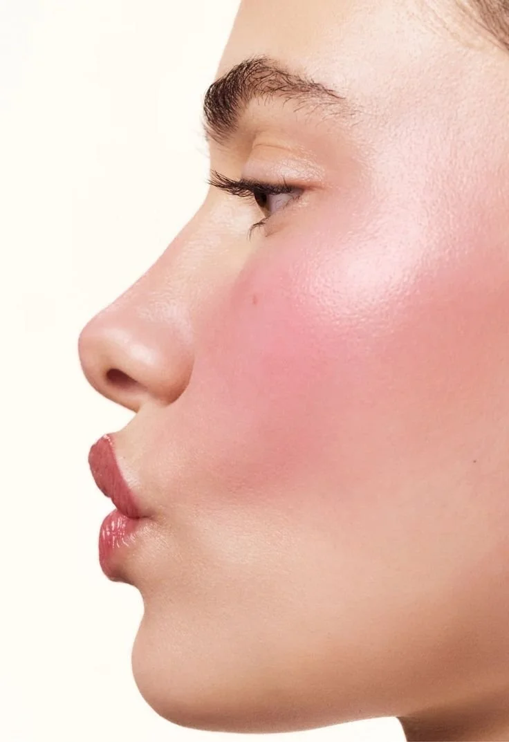 Primo piano di un volto femminile di profilo con trucco leggero e pelle levigata.