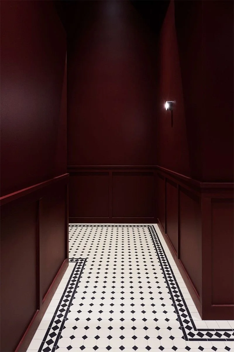 Ingresso con pareti di colore rosso scuro e pavimento a mosaico bianco e nero