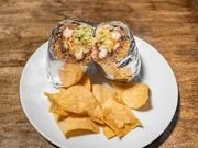 Plate with two sushi rolls and a side of potato chips on a wooden table.