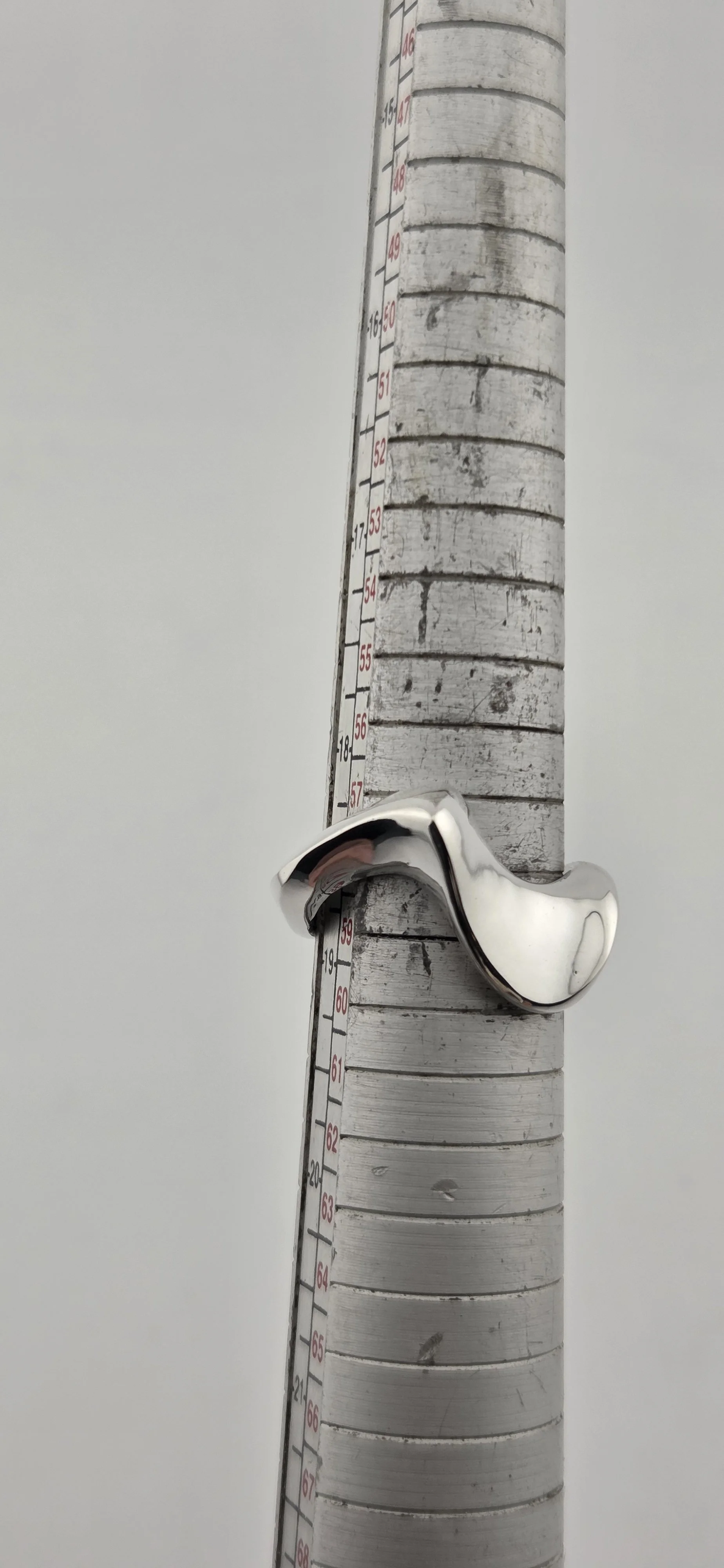 Close-up of a thermometer with a metallic handle, mounted on a wooden surface, with temperature markings from 50 to 66 degrees Fahrenheit.