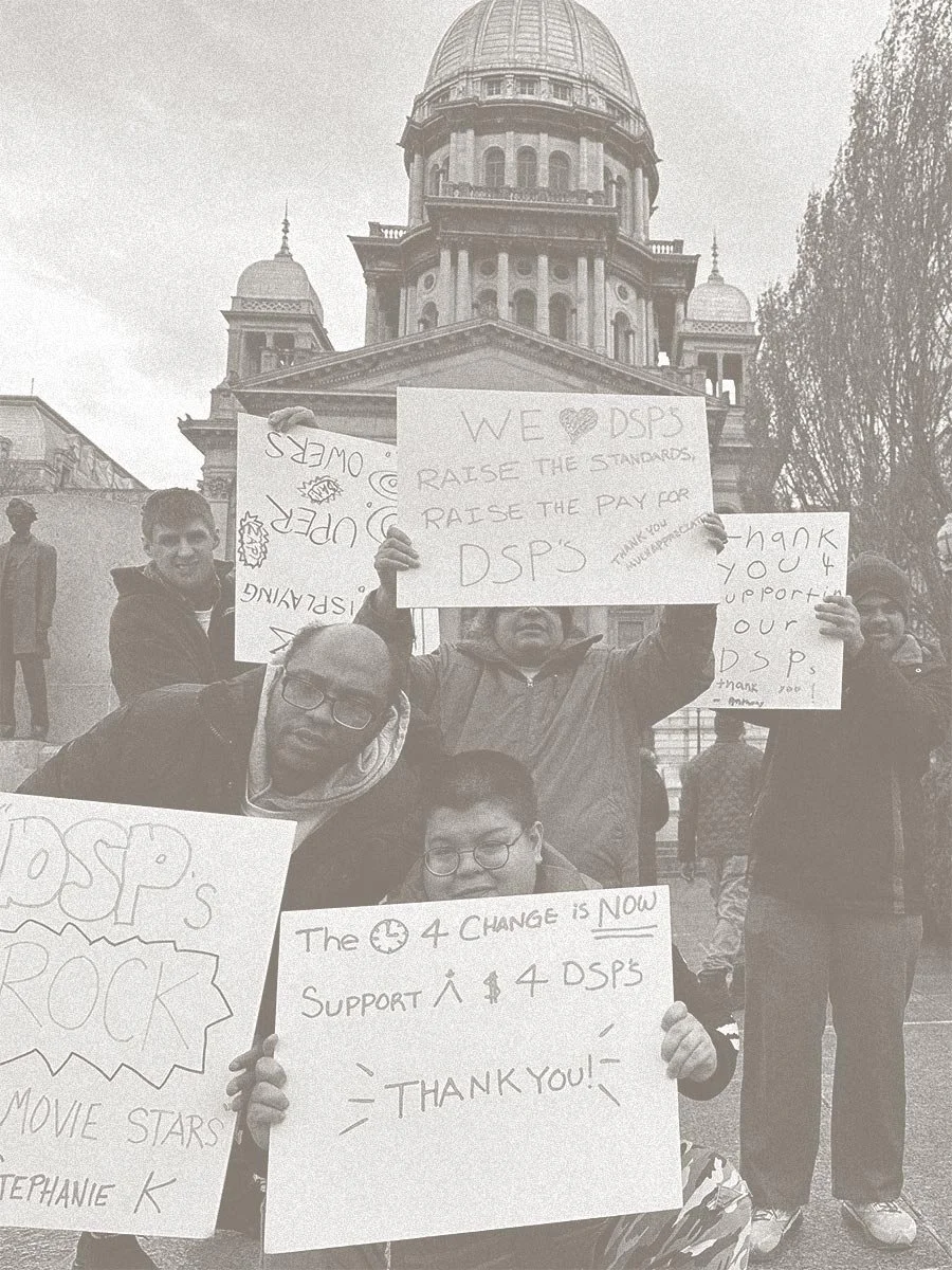 people holding signs outside Illinois capitol building advocating for DST wages and systems