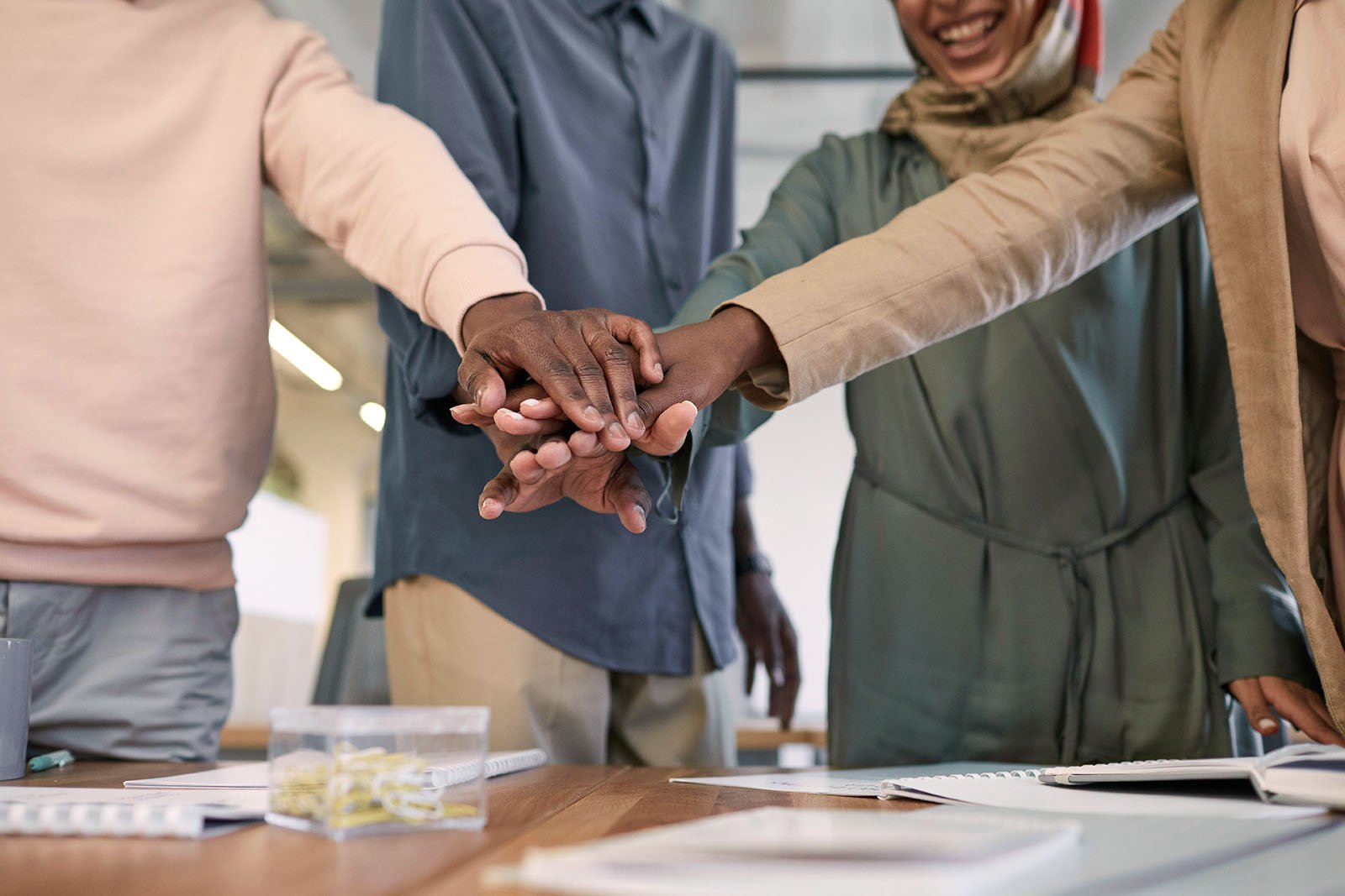 team members putting hands together in center to represent nonprofit collaboration, mergers, and partnerships