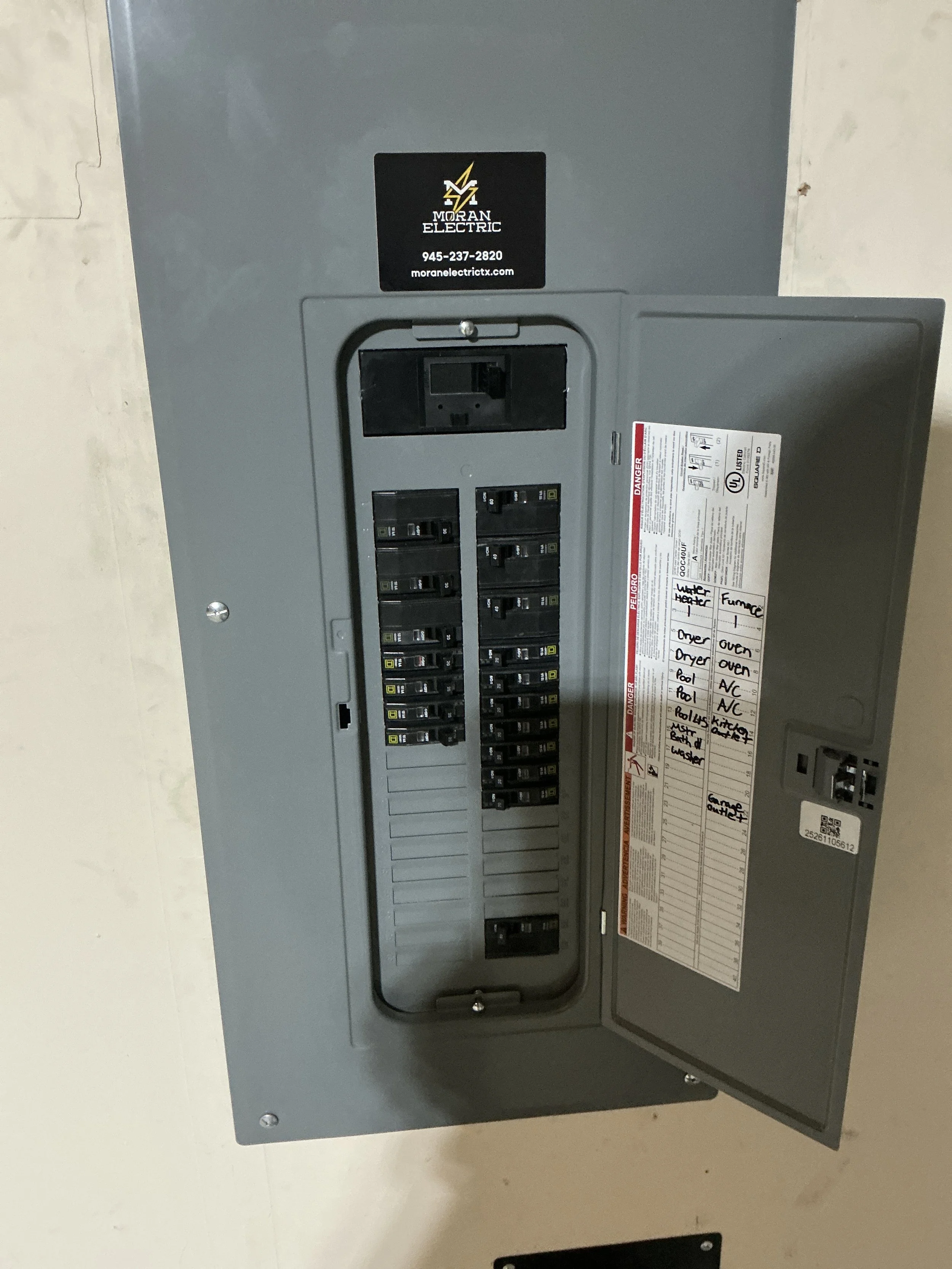 Electrical breaker box with labels for kitchen appliances and water heater, mounted on a wall.