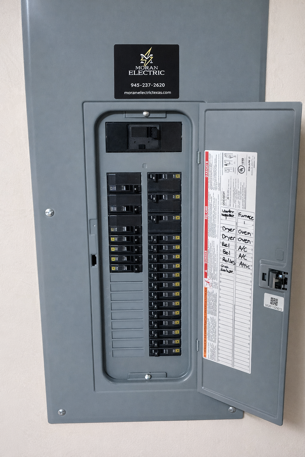 Electrical breaker box with labels for kitchen appliances and water heater, mounted on a wall.