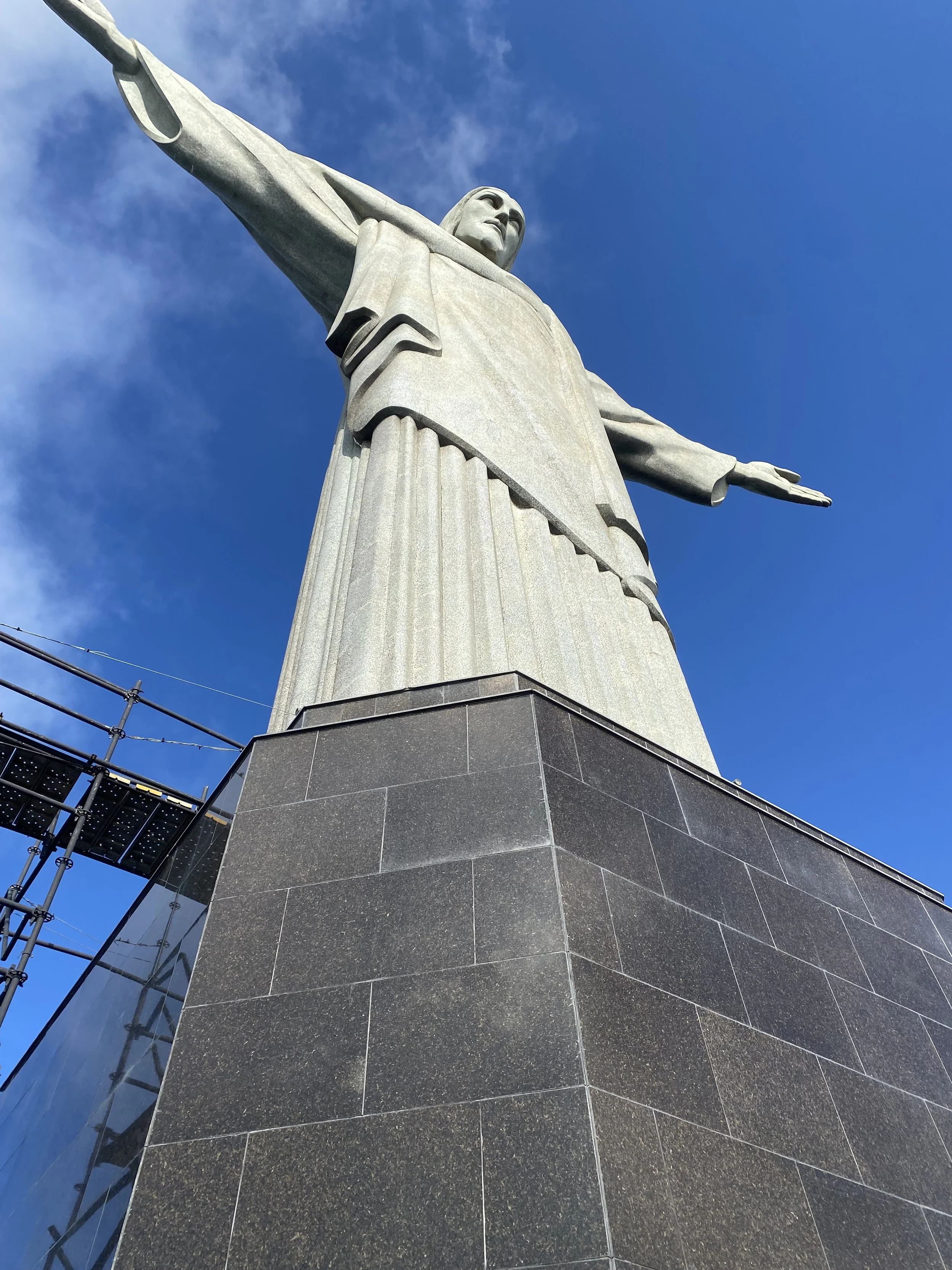 Low-angle view of the Christ the Redeemer statue against a blue sky with some clouds.