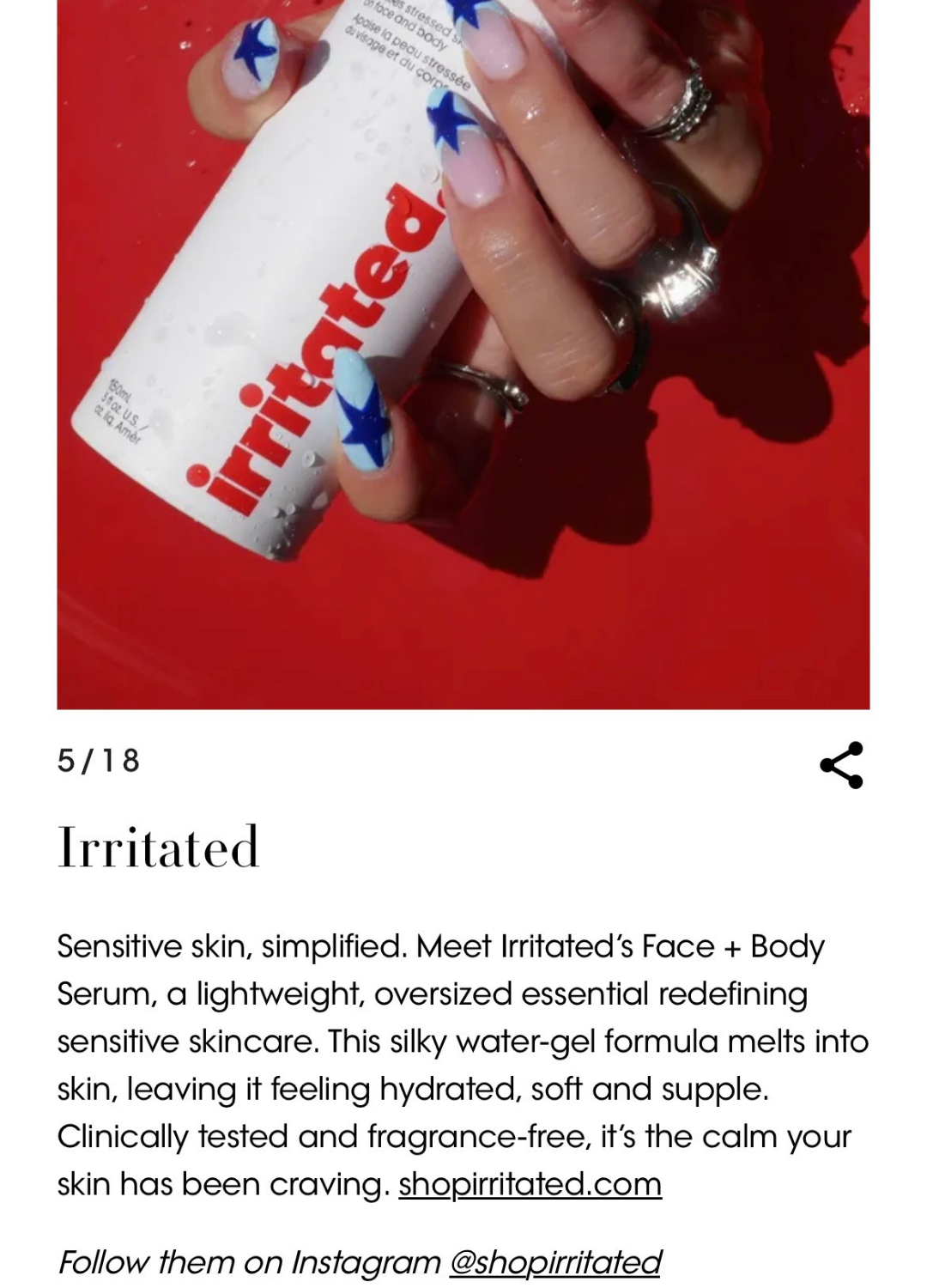 Close-up of a person's hand holding a small bottle of Irritated skincare serum with nails painted blue and white star design, rings on fingers, against a red background, with droplets of water on the bottle.
