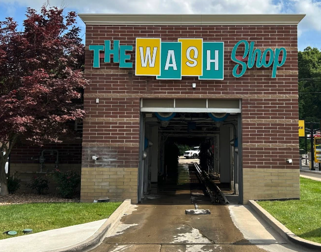 Exterior of The Wash Shop brick building featuring the express car wash tunnel entrance and retro signage.