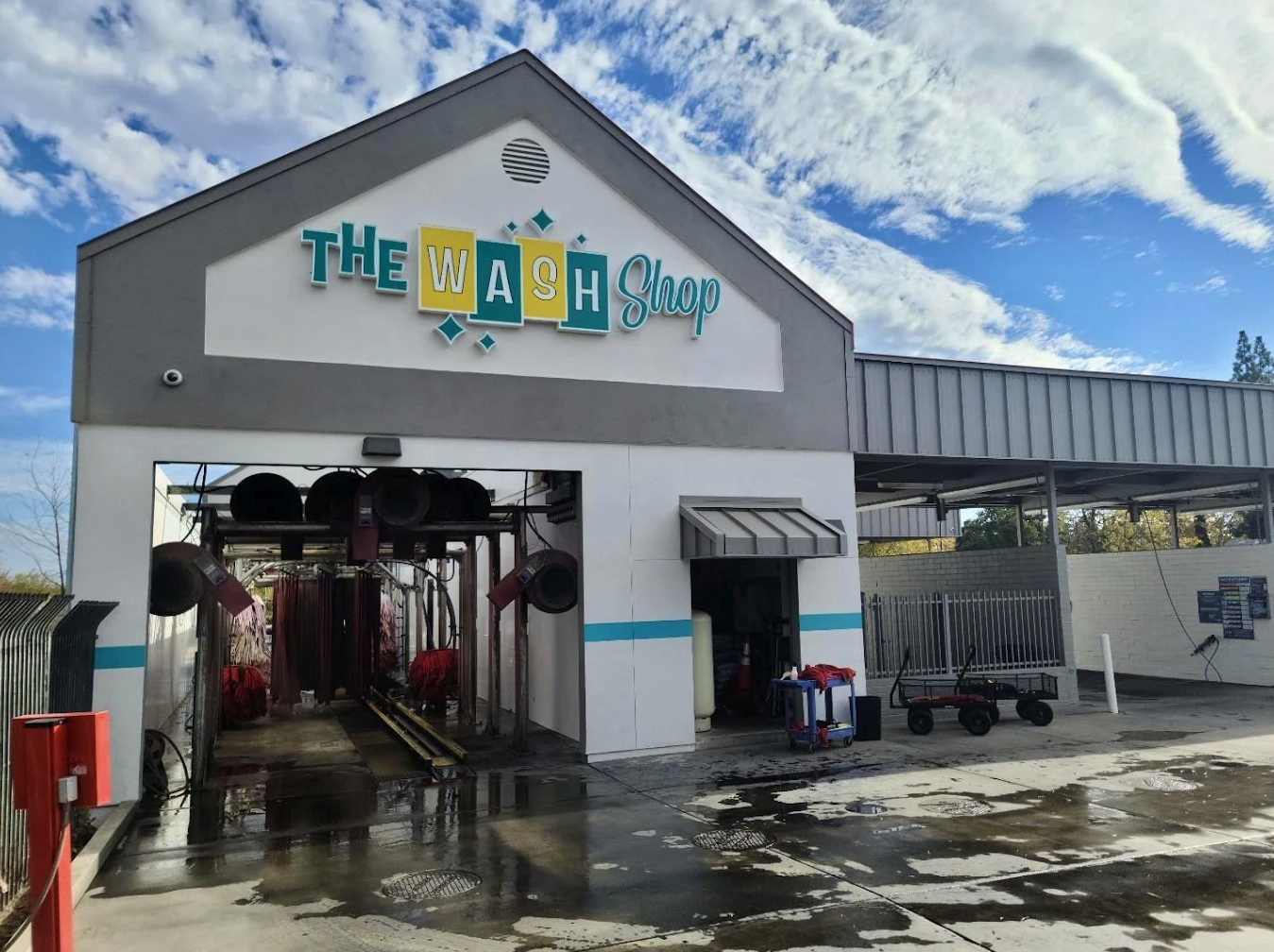 Exterior of The Wash Shop express car wash building showing the mechanical tunnel and retro brand signage.