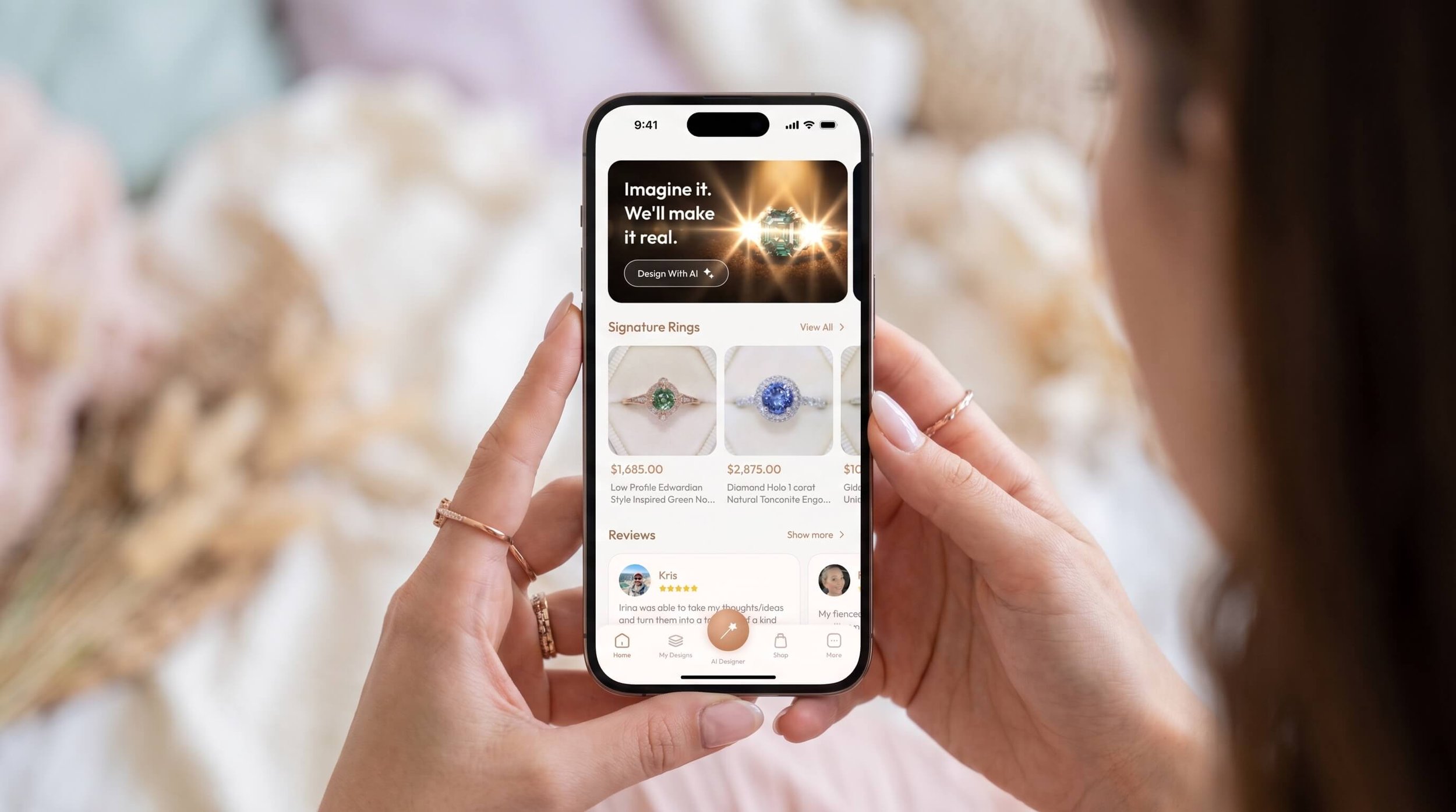 A person holds a smartphone displaying a jewelry app with signature rings, including a rose gold ring with a green round-cut gemstone in a halo setting and a white gold ring with a blue round-cut gemstone in a halo setting.