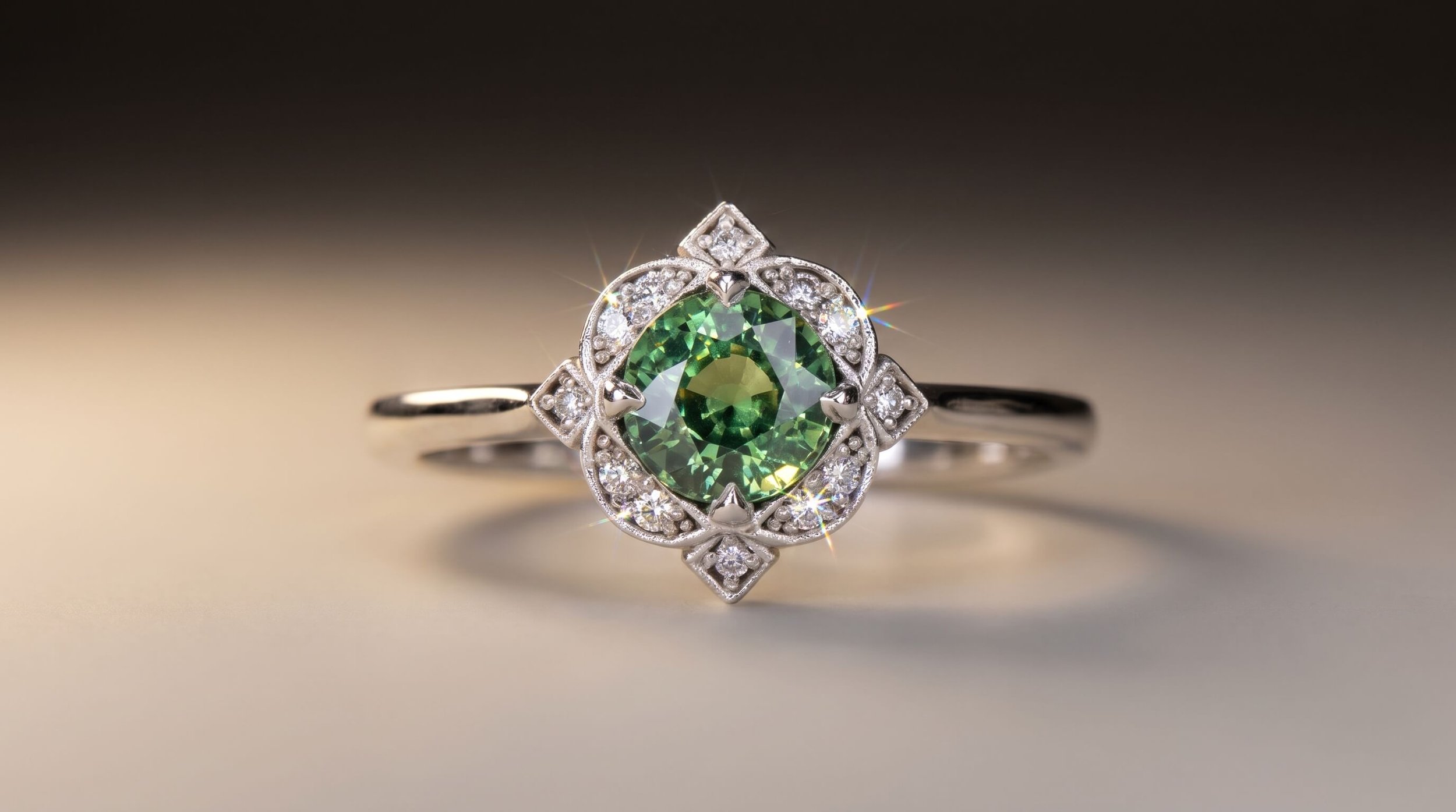 A vintage-inspired white gold ring featuring a round green gemstone in an ornate milgrain diamond halo with decorative pointed accents.