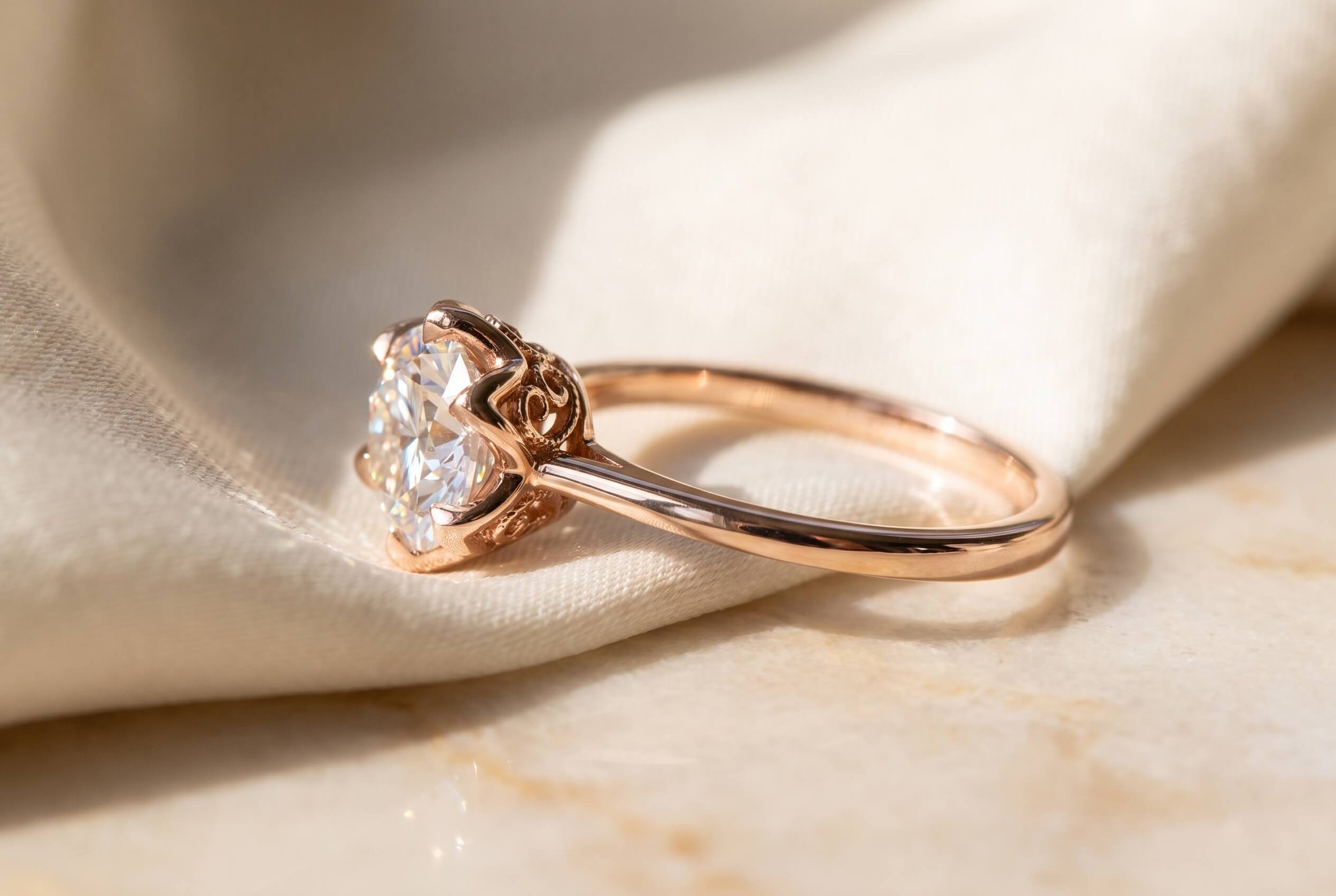 An Asscher-cut blue sapphire ring with double prongs and a diamond pavé band, displayed on draped ivory silk over marble.