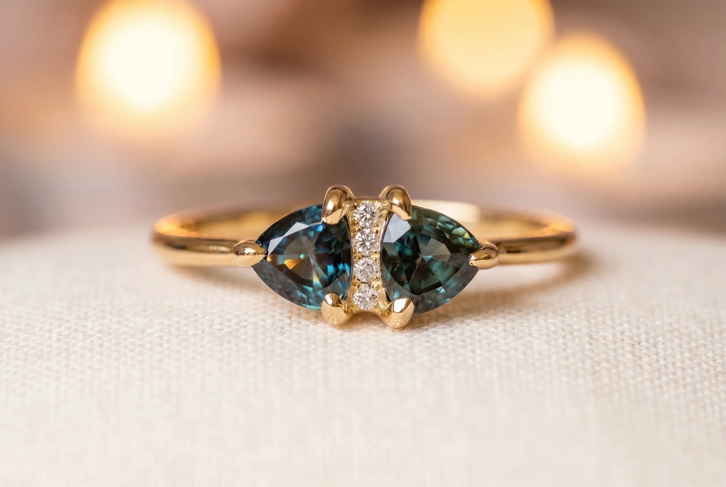 Toi et moi teal sapphire engagement ring with two pear shaped sapphires and diamond bar accent in yellow gold