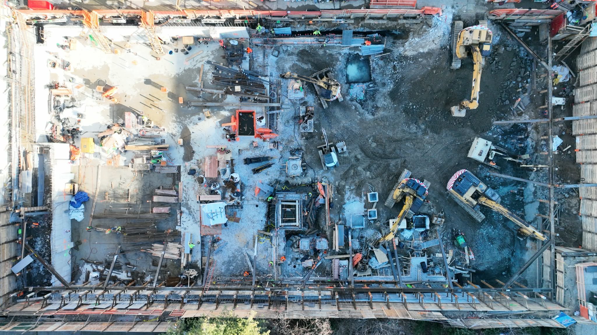 Aerial view of a construction site with machinery, workers, and building materials.