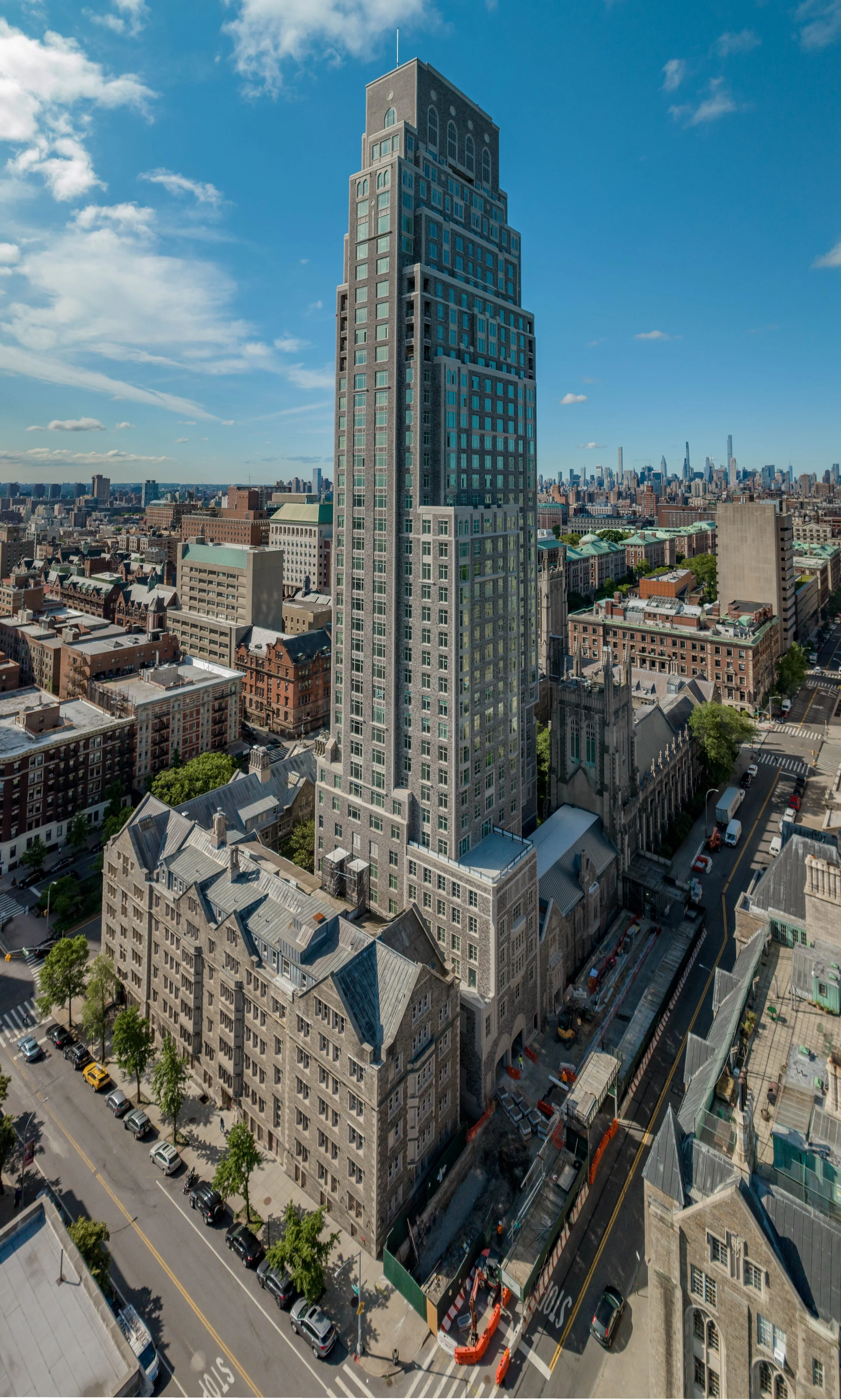 Tall skyscraper in a city with some historic buildings in the foreground, and a clear blue sky.