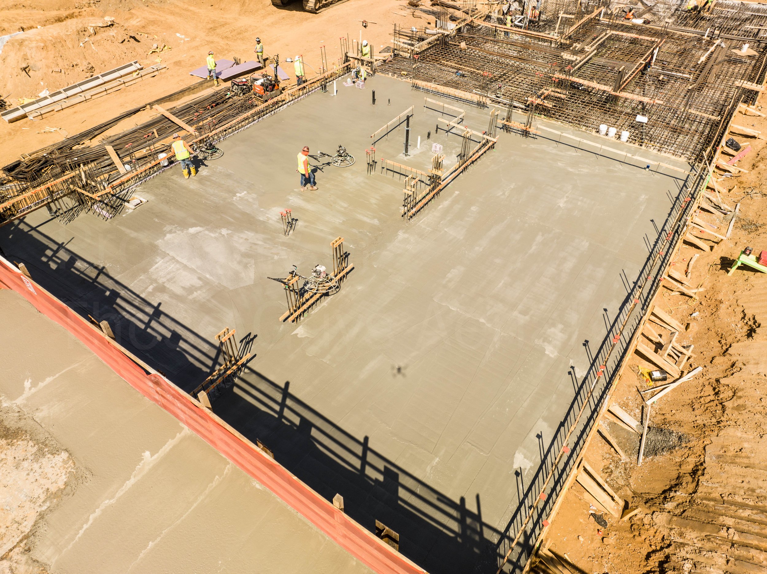 Construction workers are pouring and leveling concrete on a building foundation, with rebar and formwork in place. at 326 Rockaway Ave. Brownsville - Brookyn