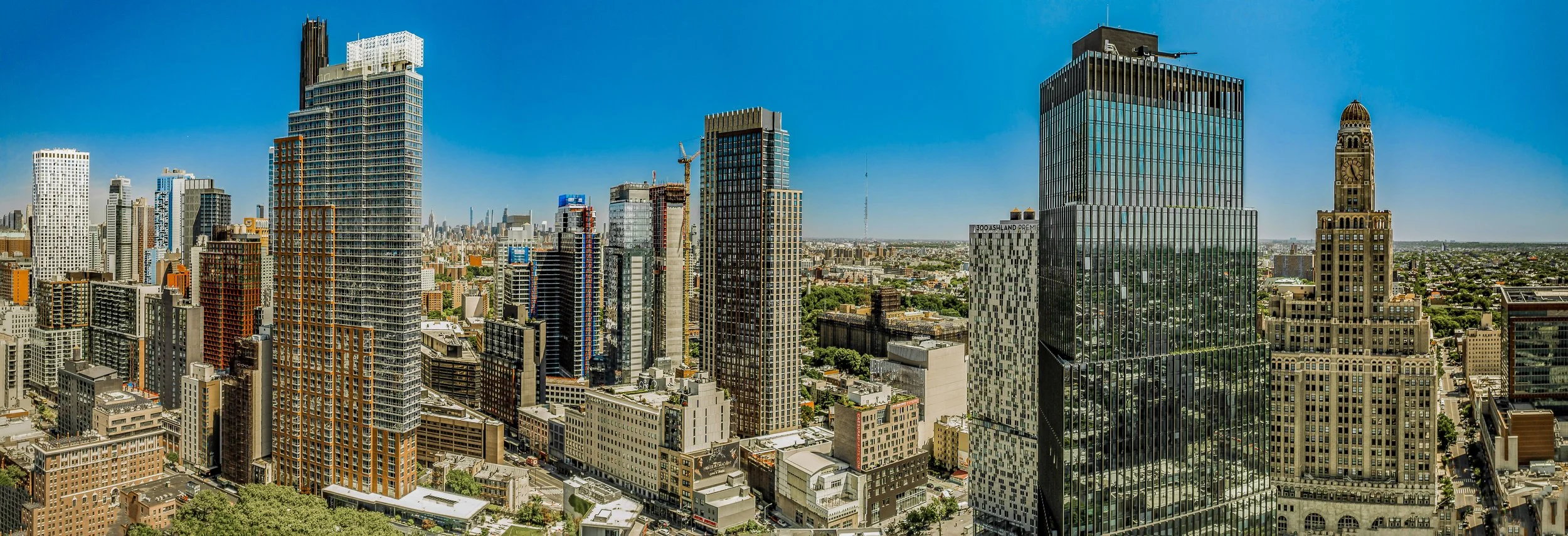 Panoramic view of a city skyline with tall modern skyscrapers under a clear blue sky.