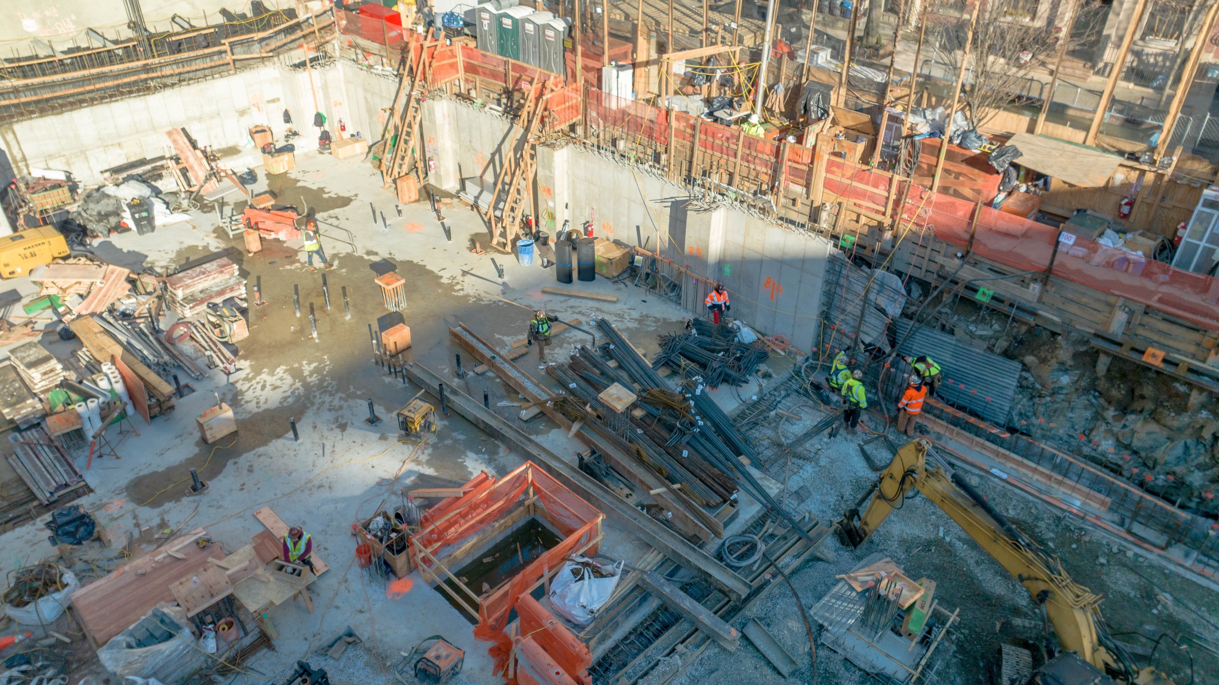 Construction site with workers in safety gear, machinery, and building materials.