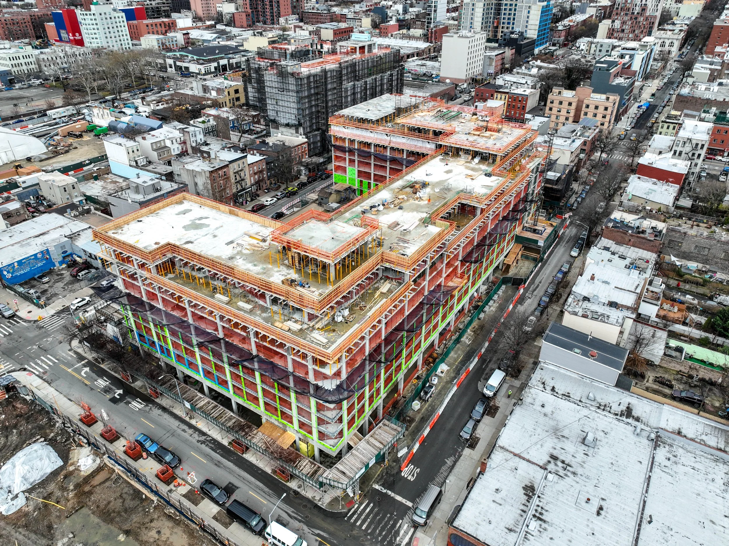 Aerial view of a large multi-story building along the Gowanus Canal under construction in an urban area, with surrounding buildings and streets visible.