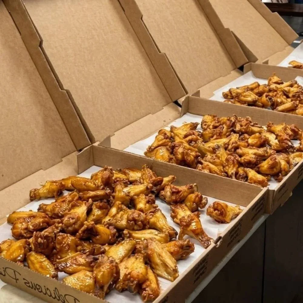 Boxes of glazed chicken wings prepared for a large order or event.
