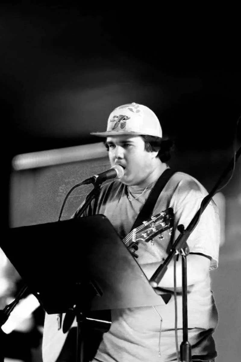 Acoustic musician performing live with guitar and microphone.
